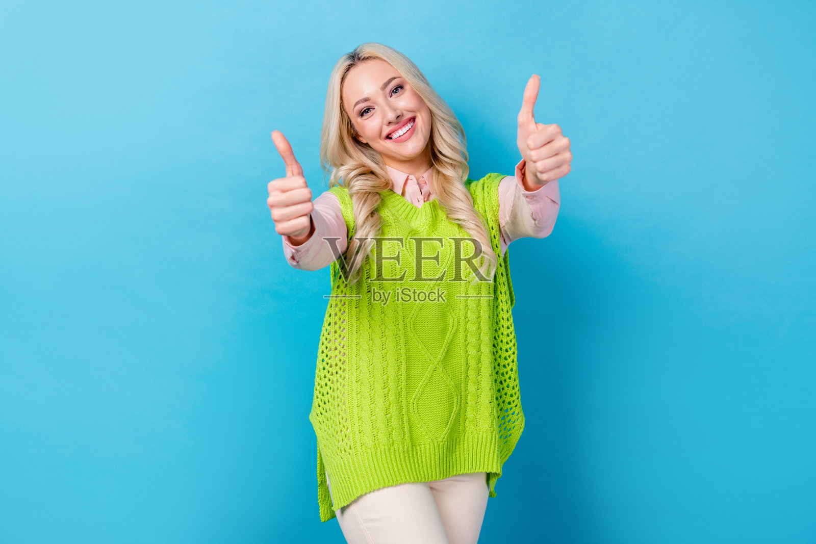 照片中兴奋的商务女士手牵着手竖起大拇指表示同意，穿着优雅的衣服孤立的蓝色背景照片摄影图片