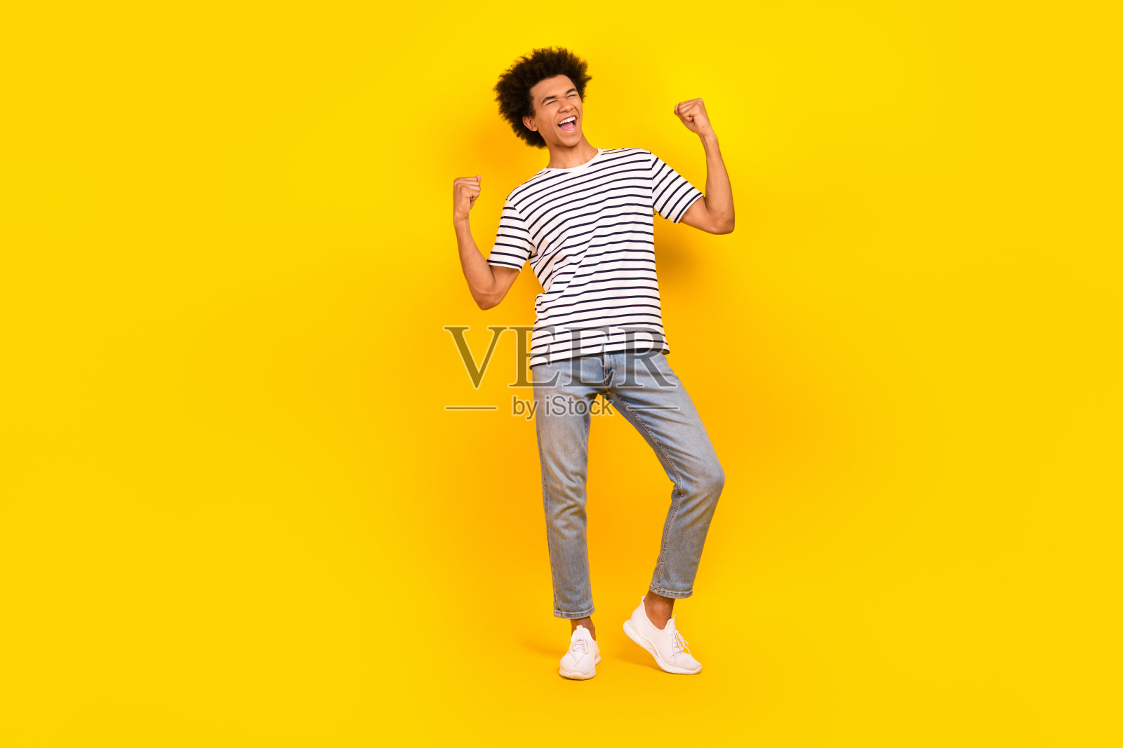 全身喜出眉外的滑稽青年男子干部举起拳头，得意洋洋地把应聘者孤立在黄色背景上照片摄影图片