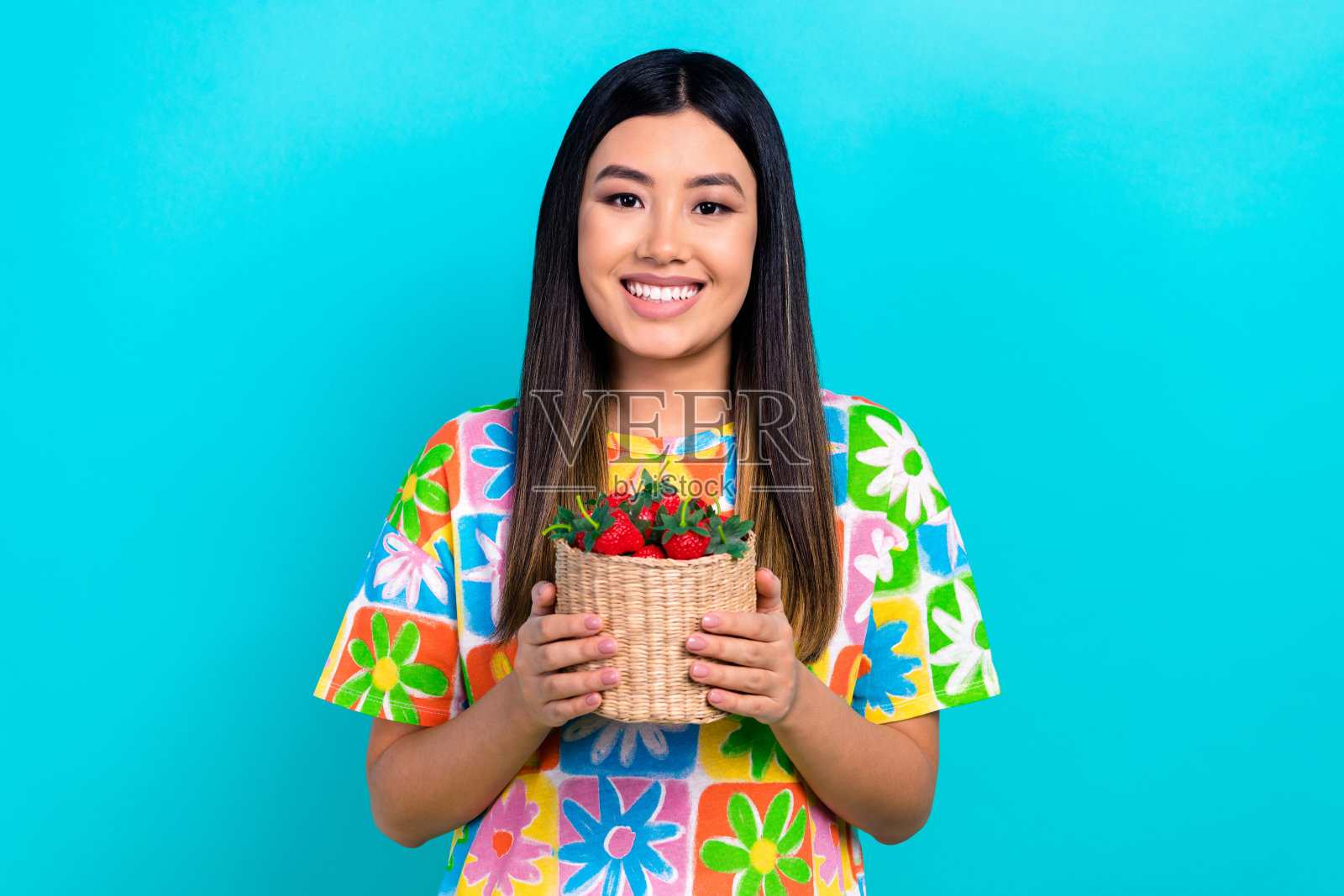 韩国年轻美丽的女士拿着草莓桶吃维他命有机食品的照片，背景是海蓝宝石色照片摄影图片