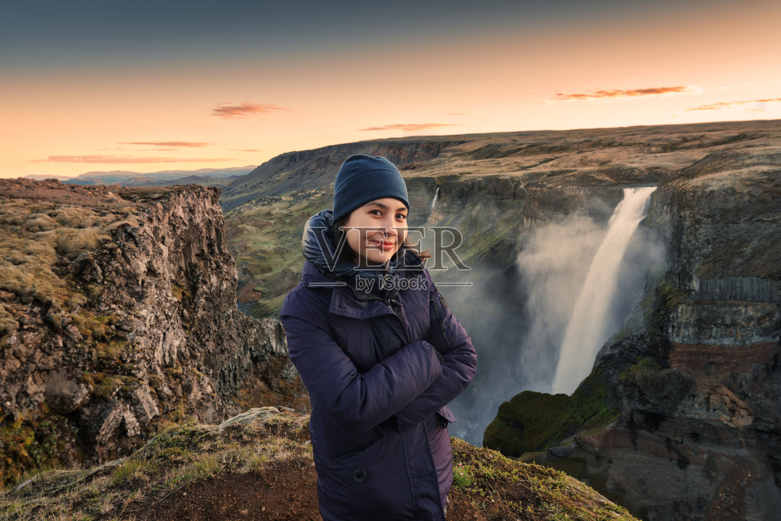 夏季，一名亚洲女子在冰岛高地欣赏海弗斯瀑布和火山峡谷的景色照片摄影图片