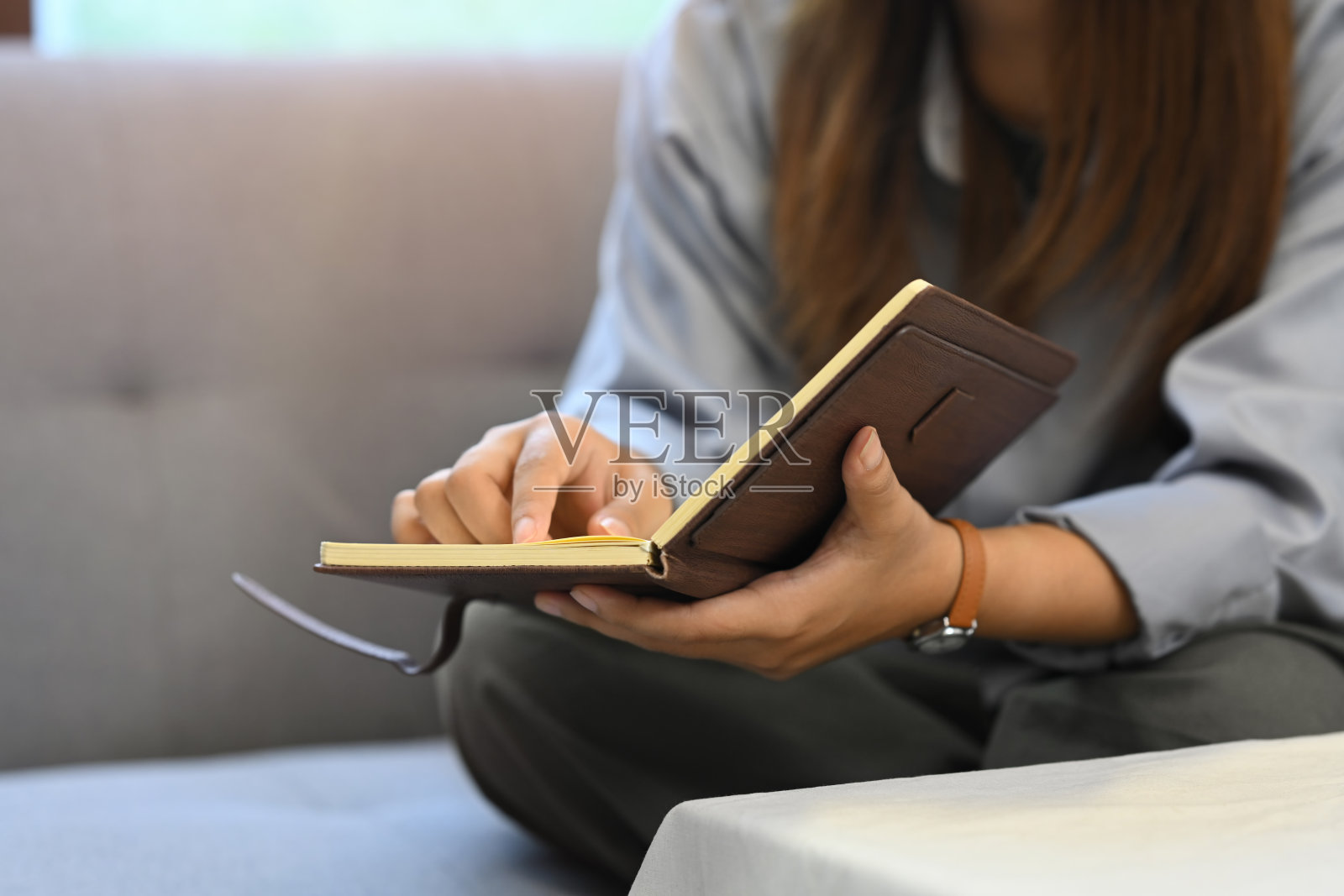 年轻女子在家里沙发上放松看书的剪影。照片摄影图片