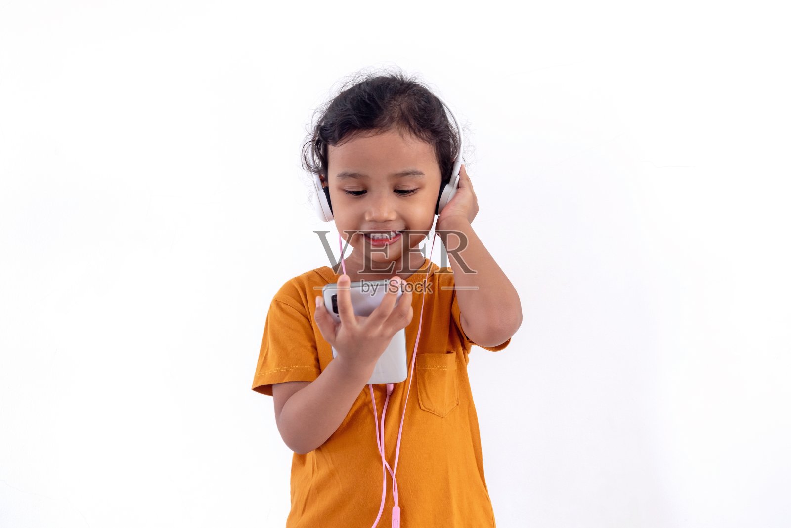 一个快乐的亚洲小女孩戴着耳机，用手机听音乐照片摄影图片