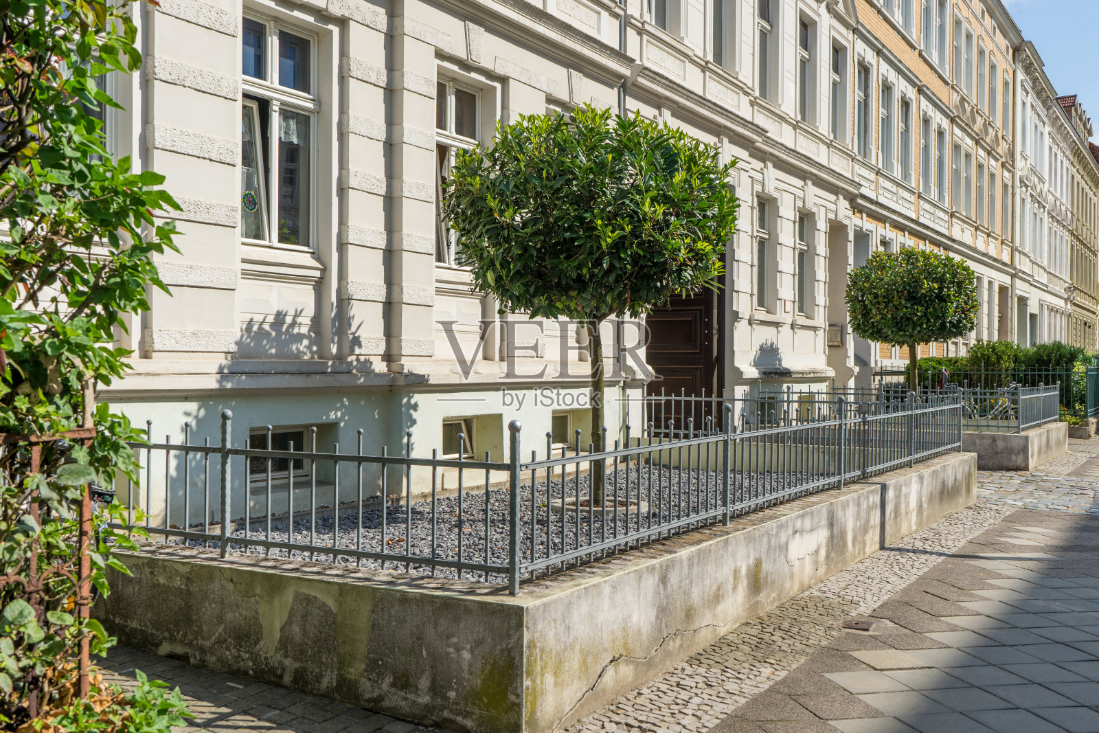 前院有金属栅栏，鹅卵石和樱桃月桂树照片摄影图片