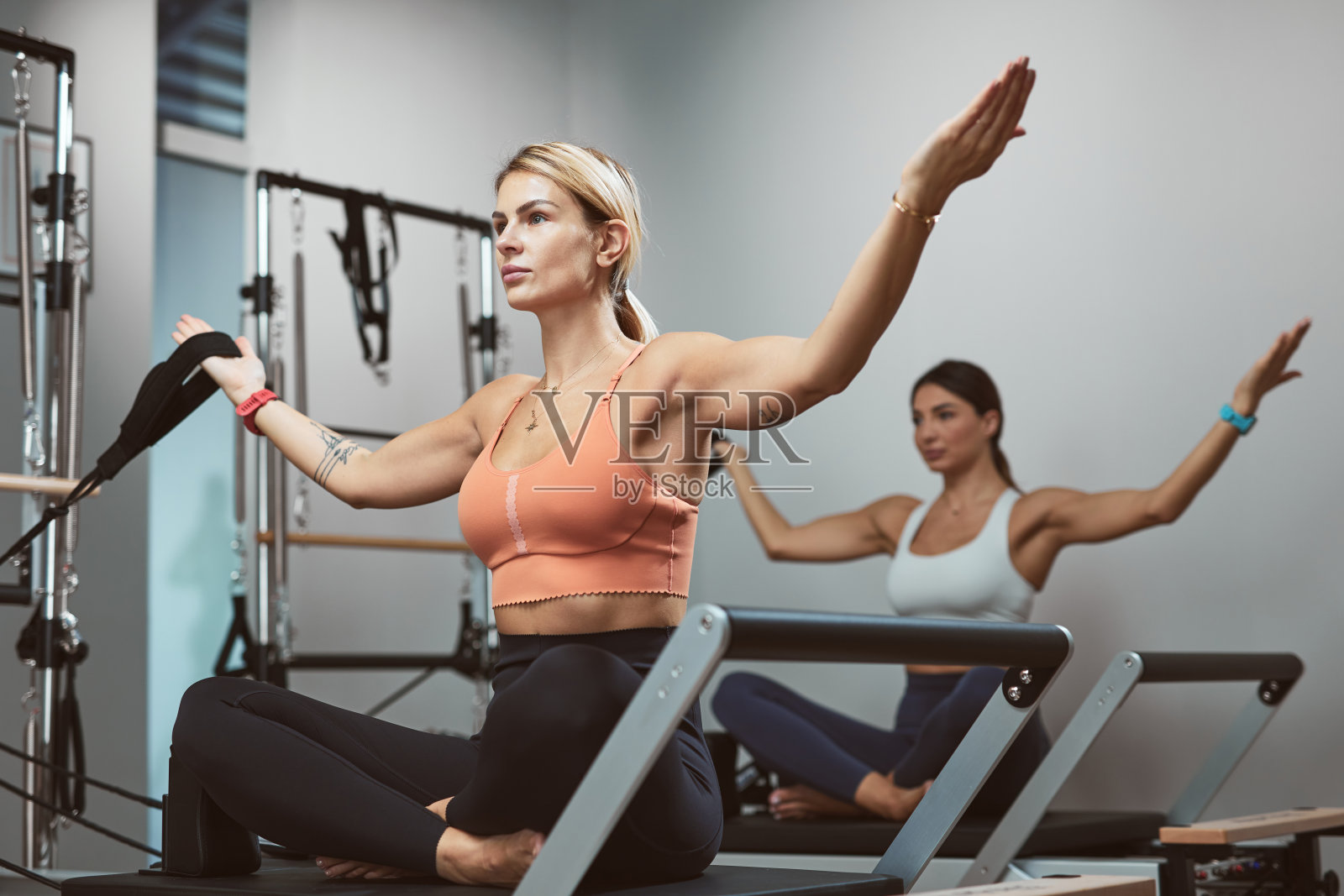 年轻女性在健身房的普拉提器械上锻炼。照片摄影图片