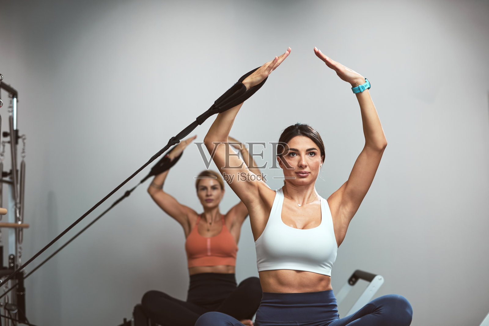 年轻女性在健身房的普拉提器械上锻炼。照片摄影图片