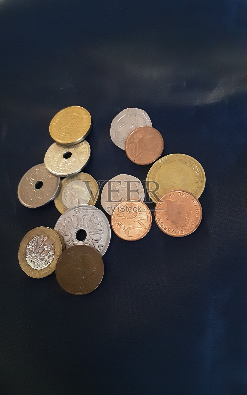 不同的硬币在黑暗的表面。照片摄影图片