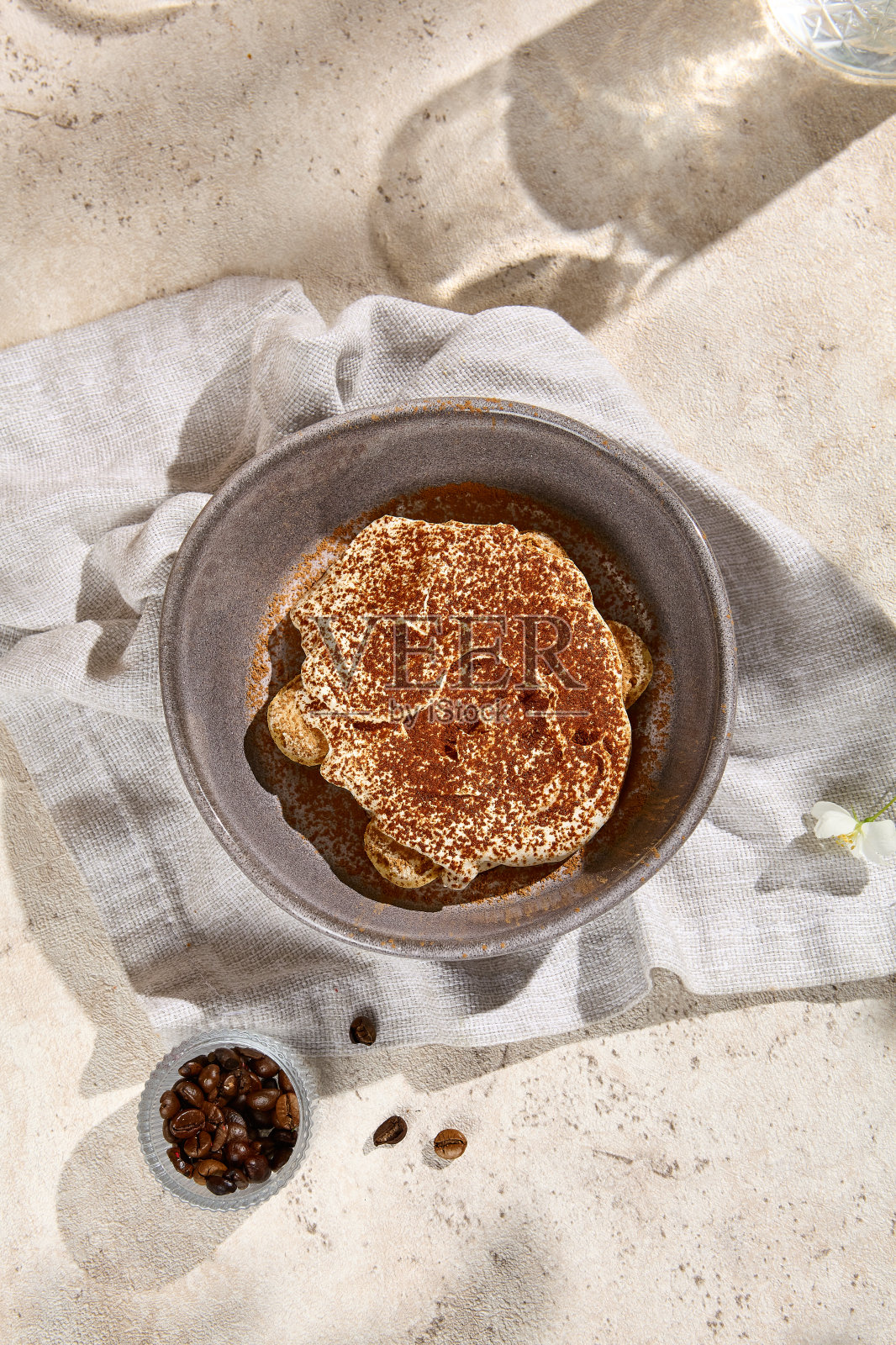 夏日阳光下的提拉米苏甜点部分与咖啡豆在浅色背景照片摄影图片