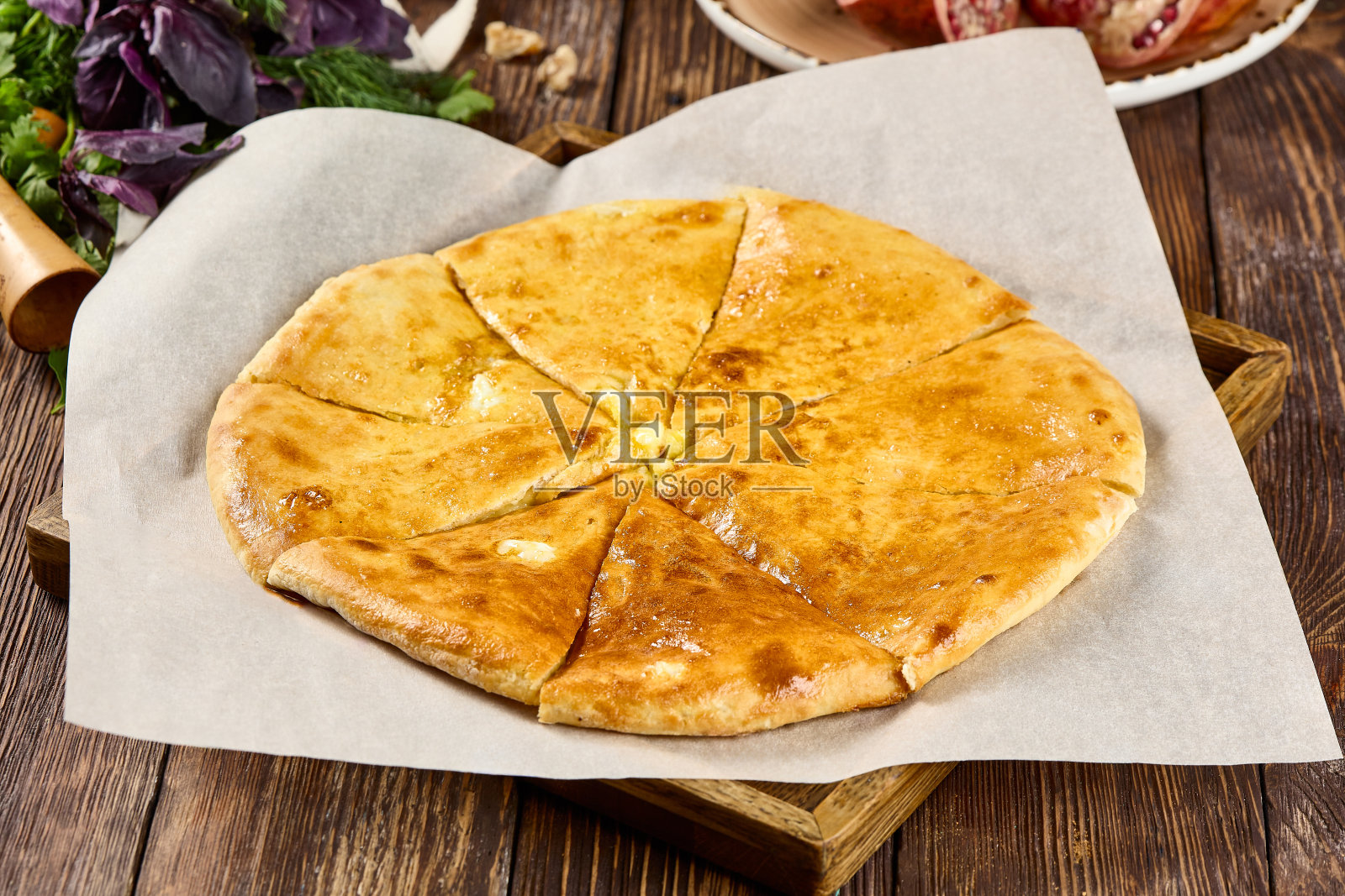 美味的奥塞梯奶酪派:一种传统的圆形面饼，在羊皮纸上切成片照片摄影图片