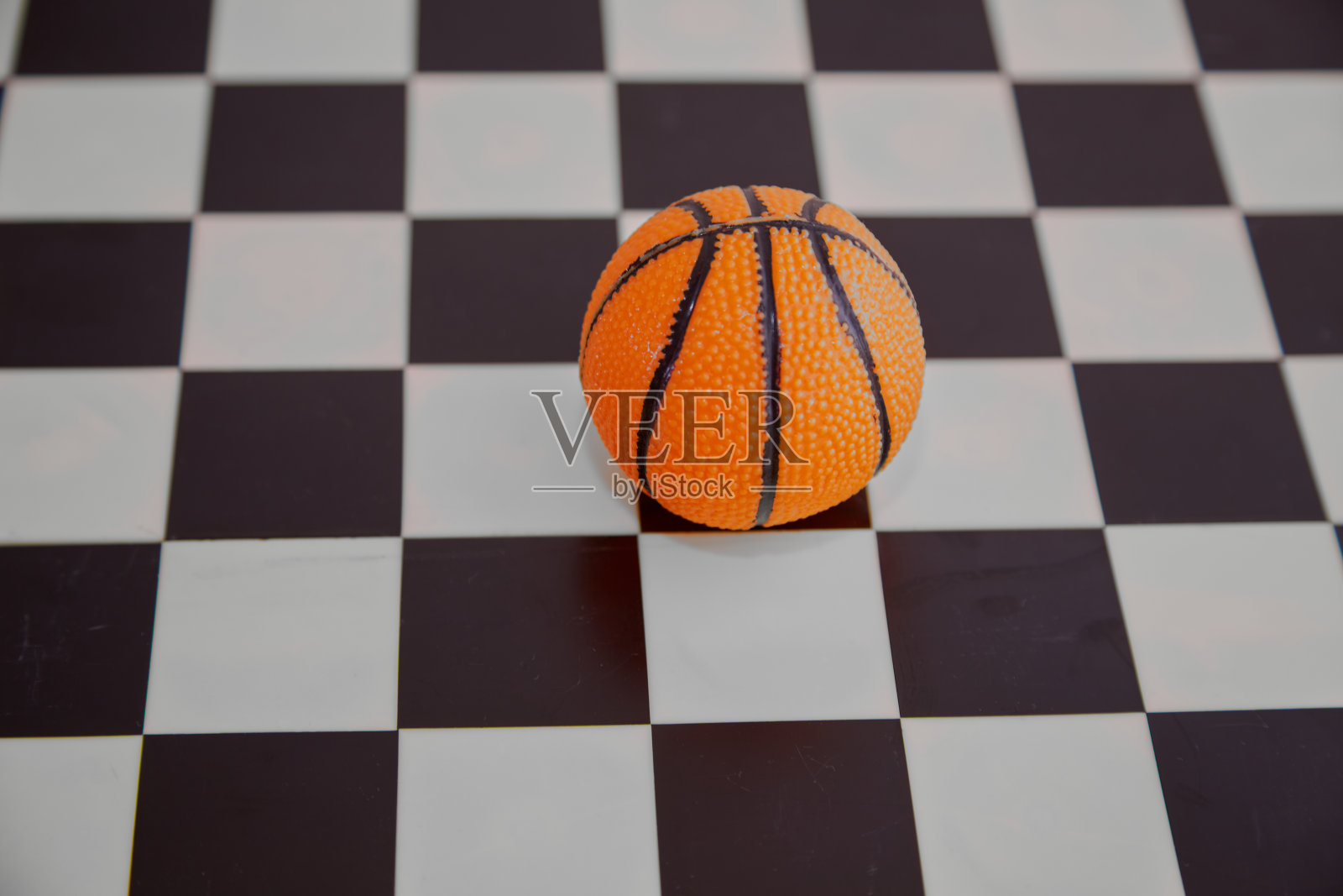 黑白棋盘上的橙色篮球特写。脑力运动，运动中的思维速度，篮球中的思维速度。照片摄影图片