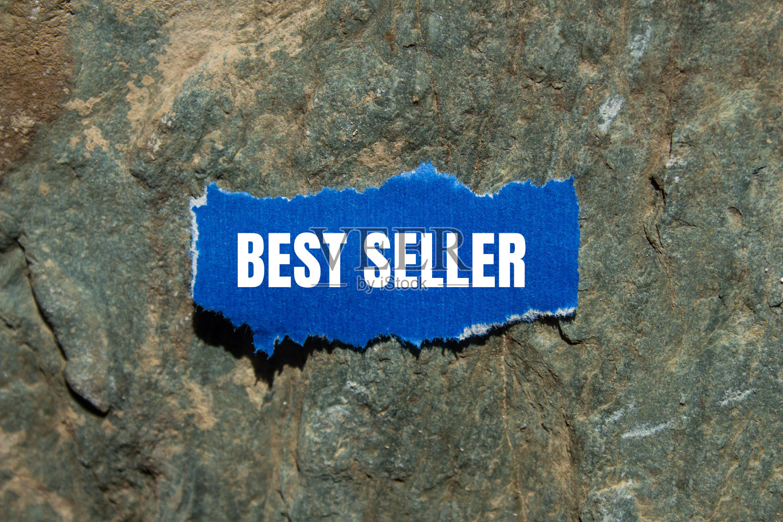 最畅销的信息写在撕开撕开的蓝色纸块在石头的背景照片摄影图片