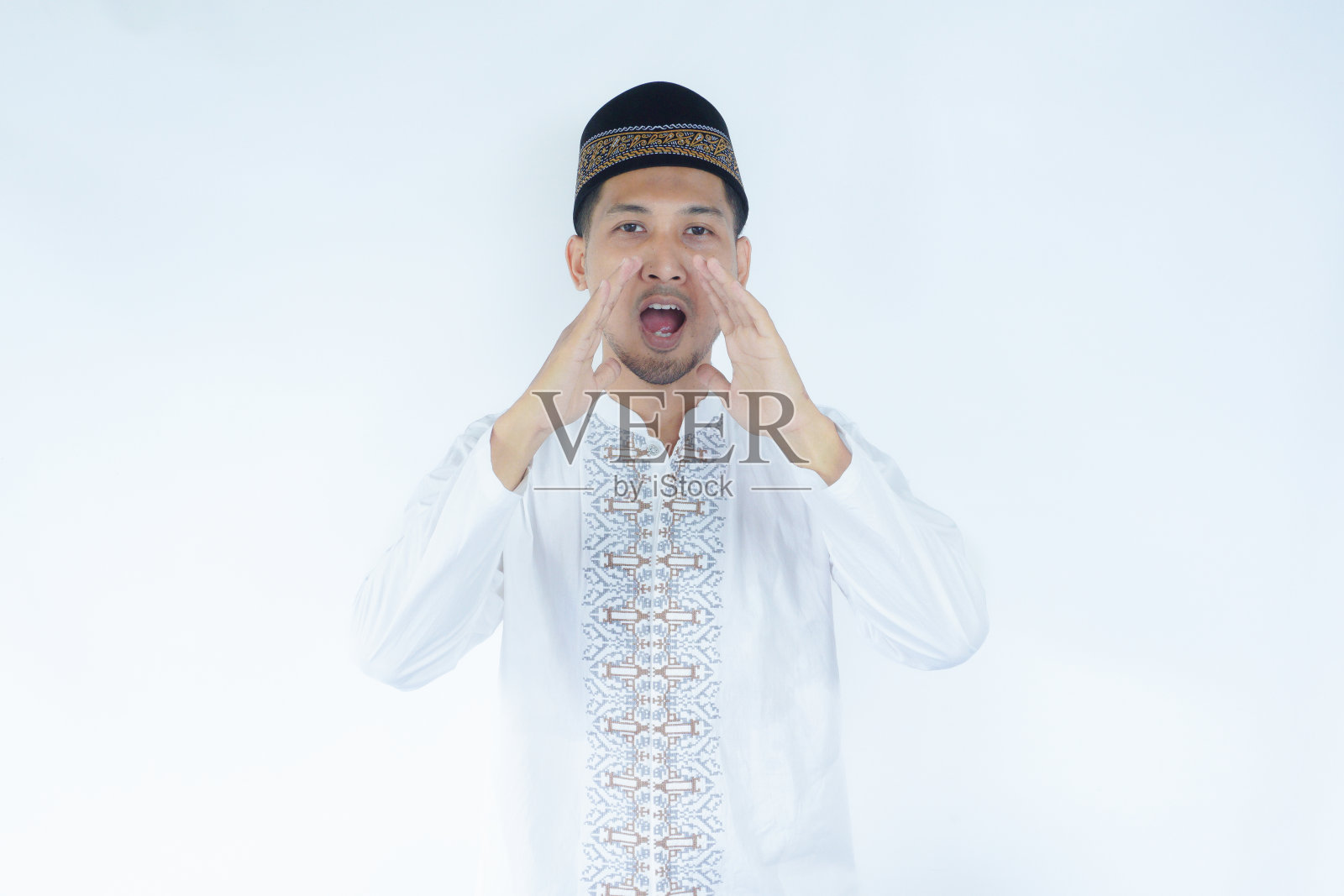 年轻的亚洲穆斯林男子兴奋地喊着说着什么。隔离在白色背景上照片摄影图片