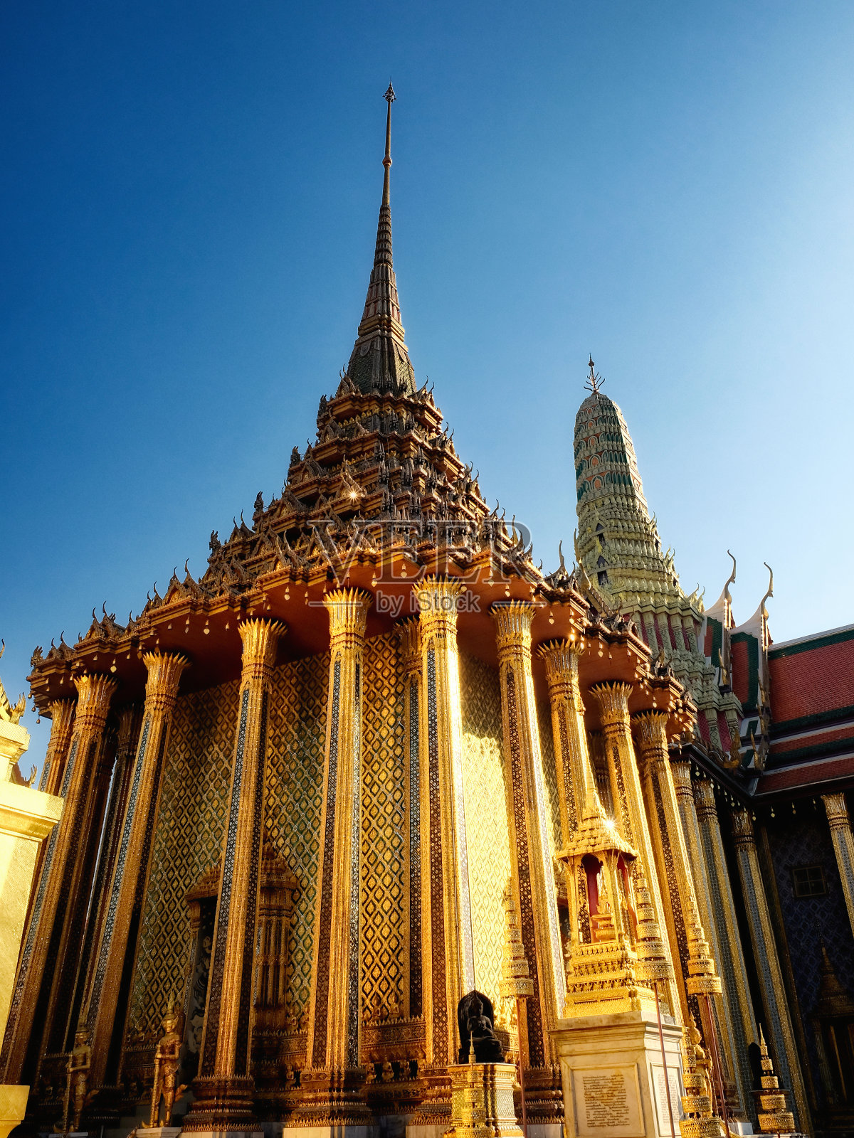 一个泰国的圣殿，闪耀着镀金的尖塔和精心制作的装饰，自豪地站在一个原始的蔚蓝的天空。照片摄影图片