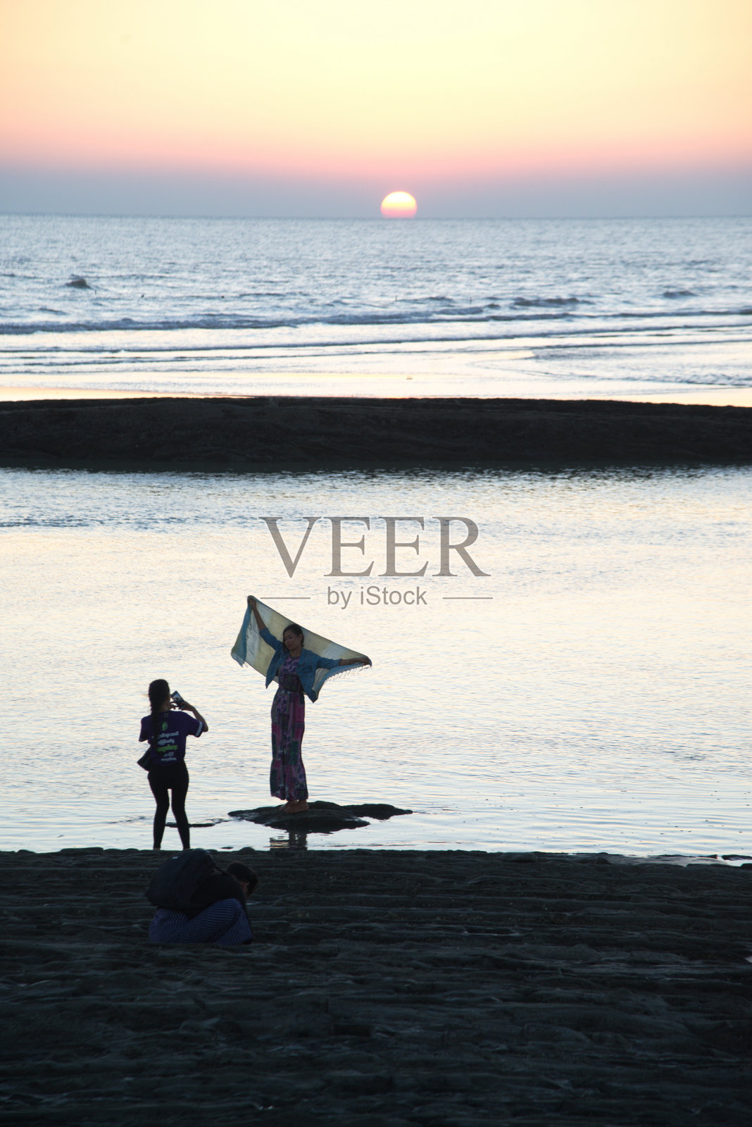 在实兑海滩，一名身份不明的游客在太阳落山时开心地自拍。照片摄影图片