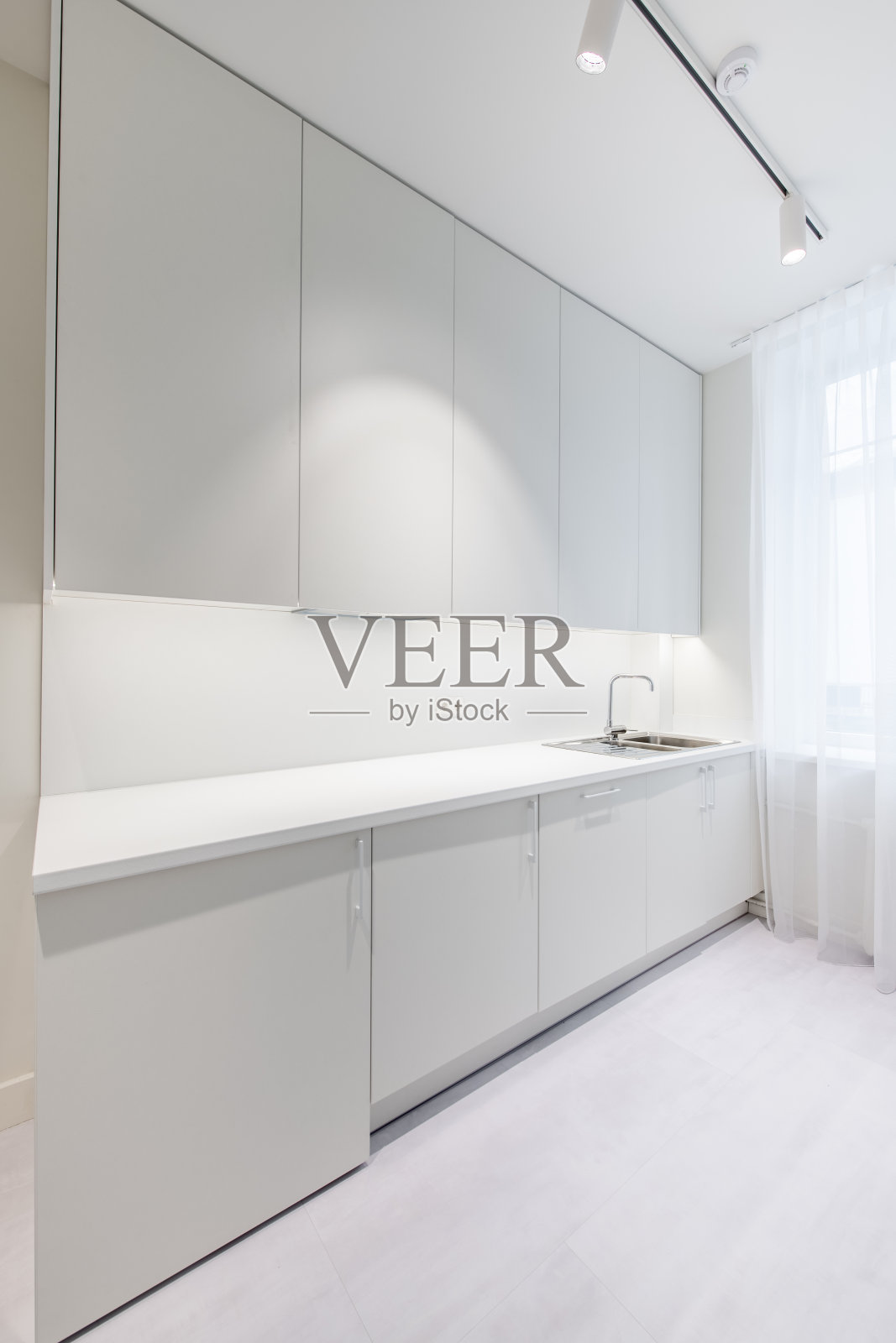 斯堪的纳维亚风格舒适现代开放明亮极简主义厨房家庭室内。烤箱，水龙头和背景家具。深棕色地板。白色的橱柜照片摄影图片