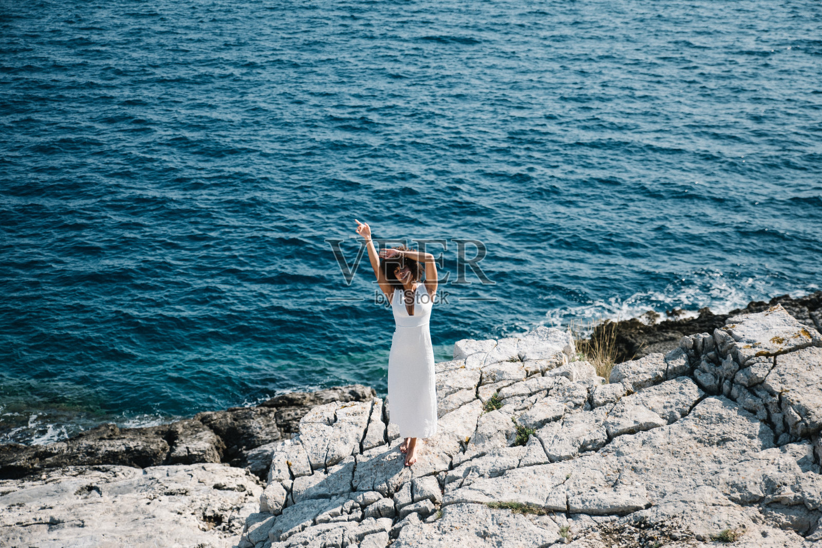 《站在海边岩石上的女人》全长照片摄影图片