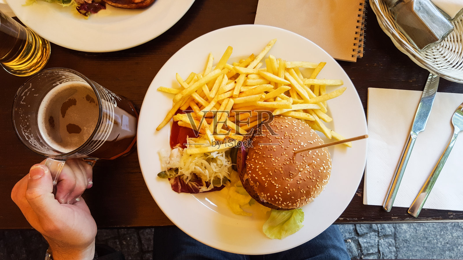 裁剪图像的人吃汉堡和啤酒在餐馆的桌子上照片摄影图片