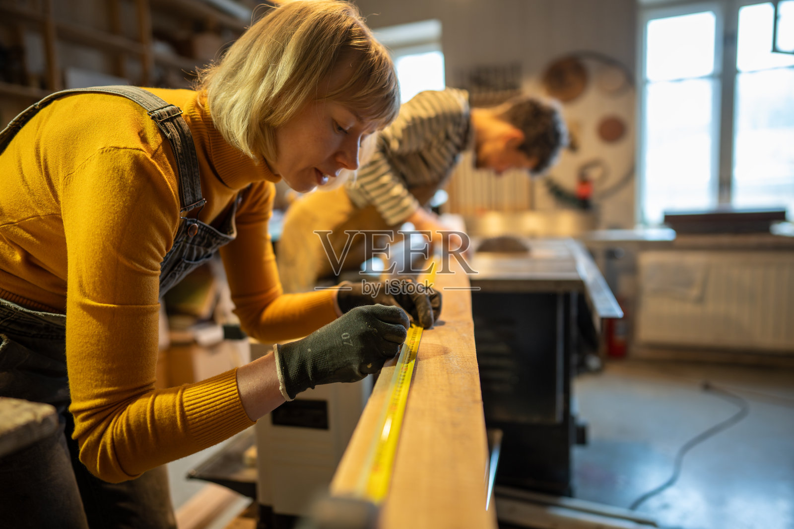女木匠在木工车间与同事在木板上标记点照片摄影图片