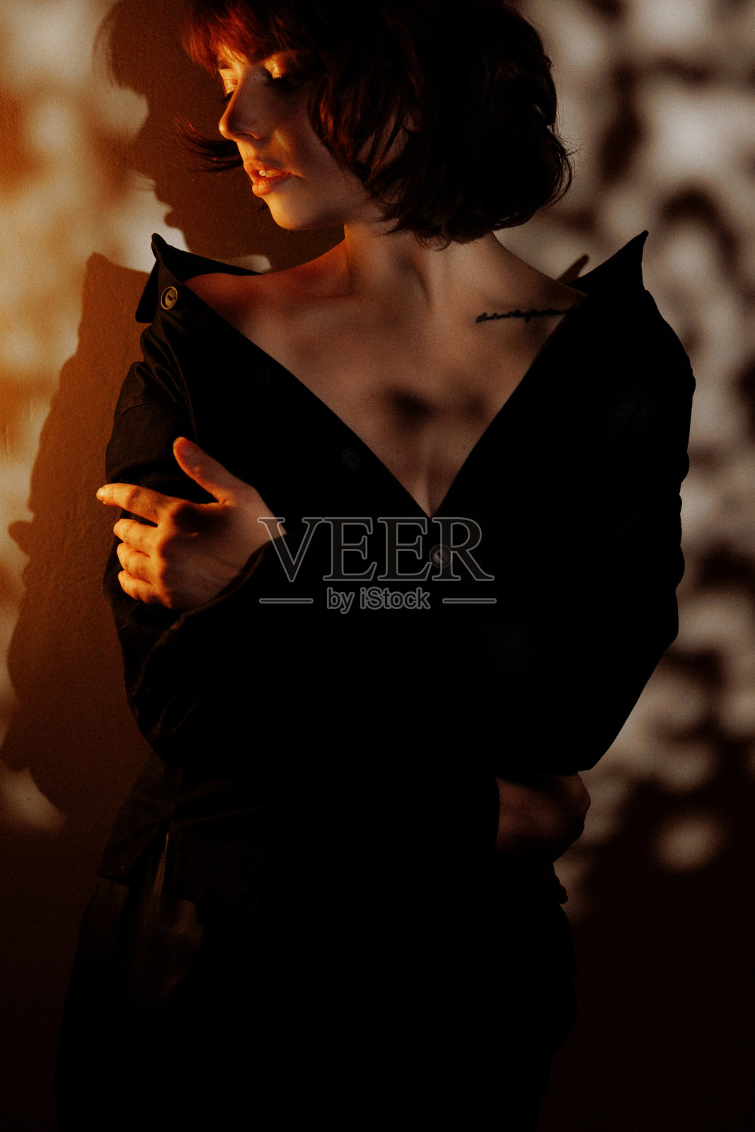 站在墙前的女子与戏剧性的阴影照片摄影图片