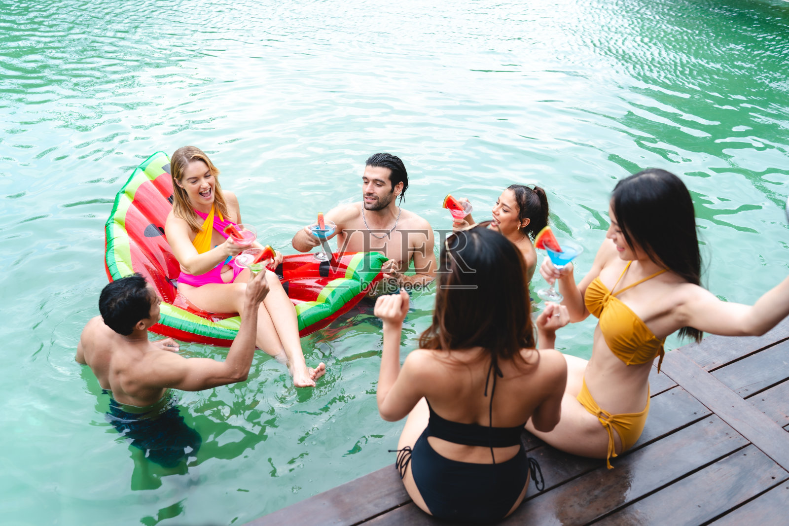 夏日泳池派对乐趣:穿着泳装的朋友们一起享受快乐的时刻，一群年轻男女在水边创造友谊和欢笑的快乐回忆照片摄影图片