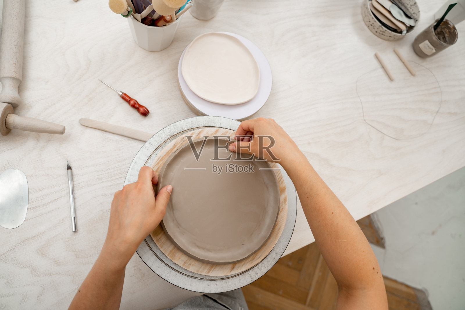 粘土制品的建筑边。板陶器。用平坦的粘土制作陶瓷制品。用手为一个粘土项目建模。照片摄影图片