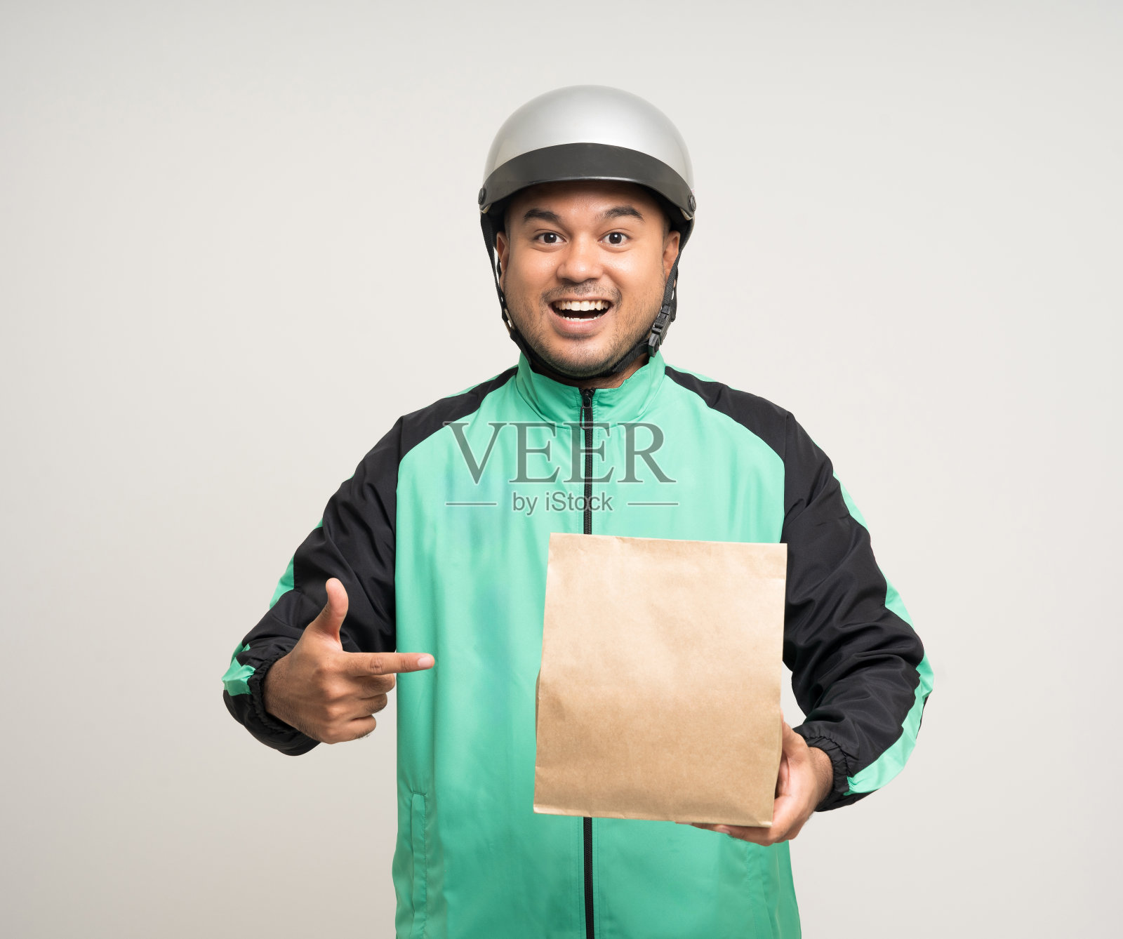 年轻的亚洲骑手穿着绿色夹克制服和头盔各种动作手持食品纸袋交付给客户。男快递员。快递和运输食品服务。照片摄影图片