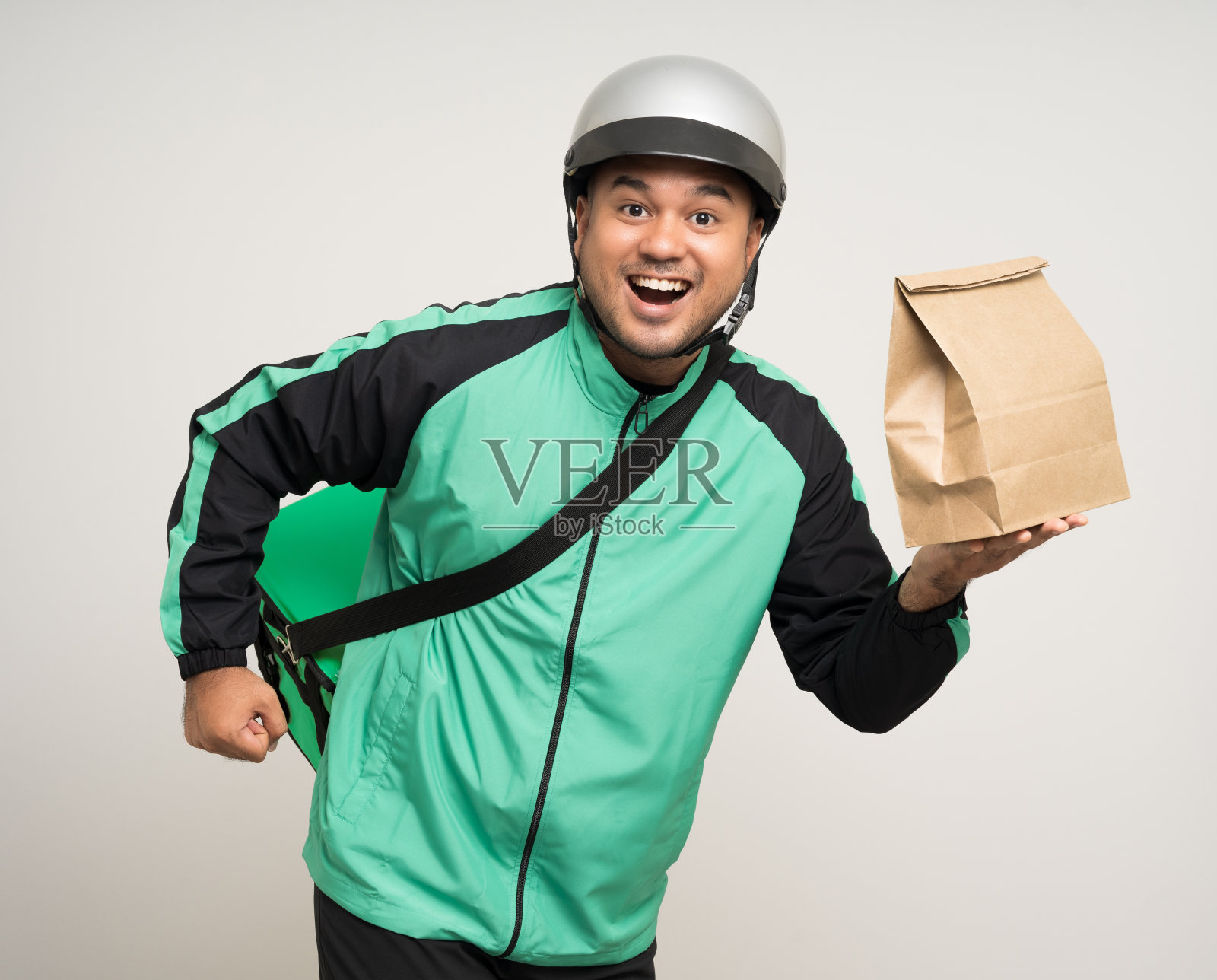 年轻的亚洲骑手穿着绿色夹克制服和头盔各种动作拿着很多纸包投递箱给客户。男服务员:快递、送货、送餐服务。照片摄影图片