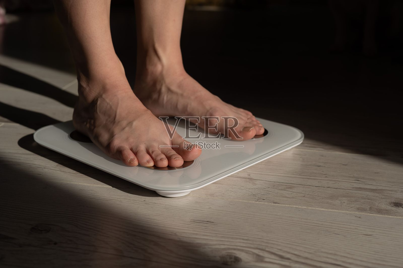 电子秤上女性腿的特写。照片摄影图片