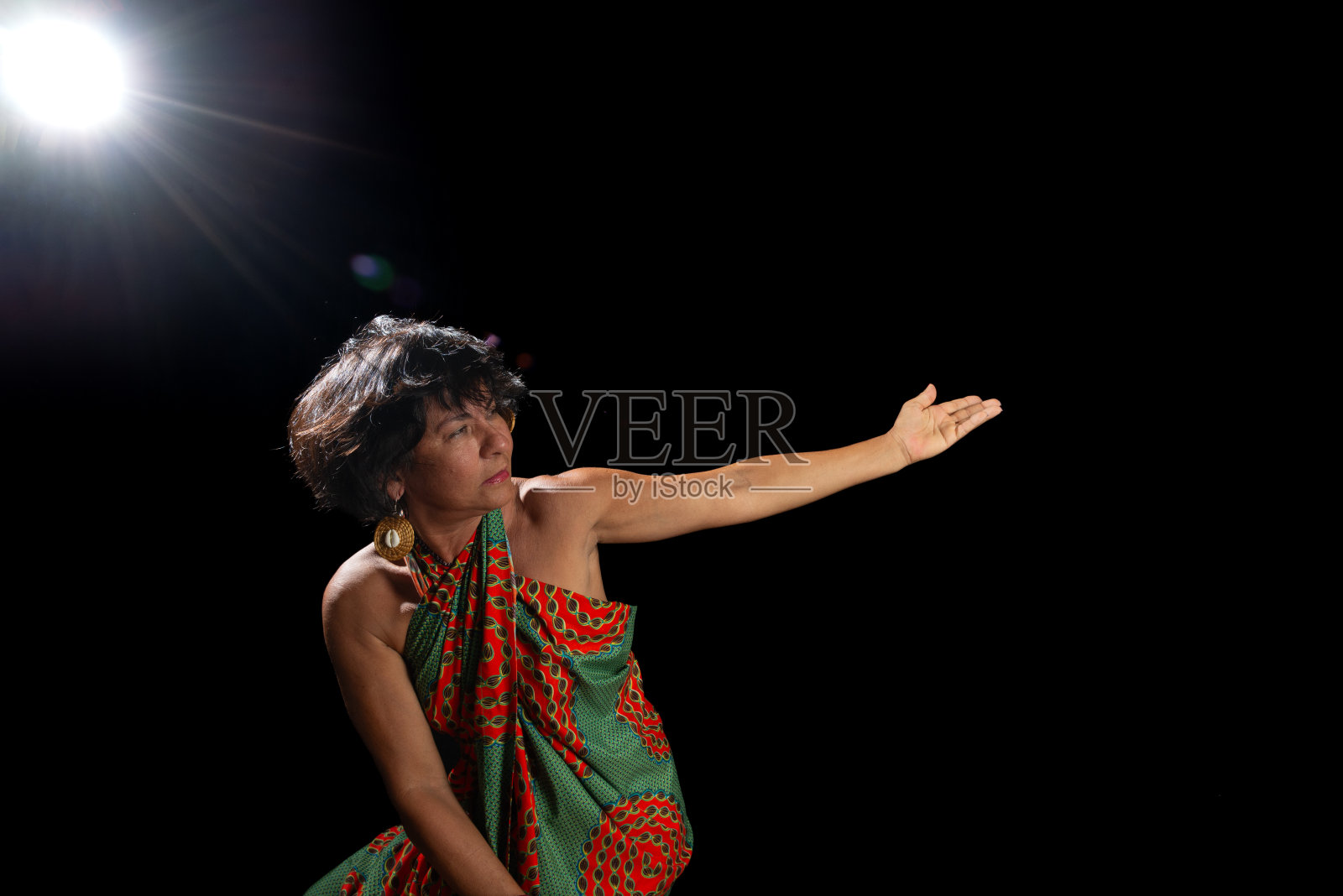 美丽的成熟的女子肖像，穿着五颜六色的衣服，坐在木凳上做身体杂技。照片摄影图片