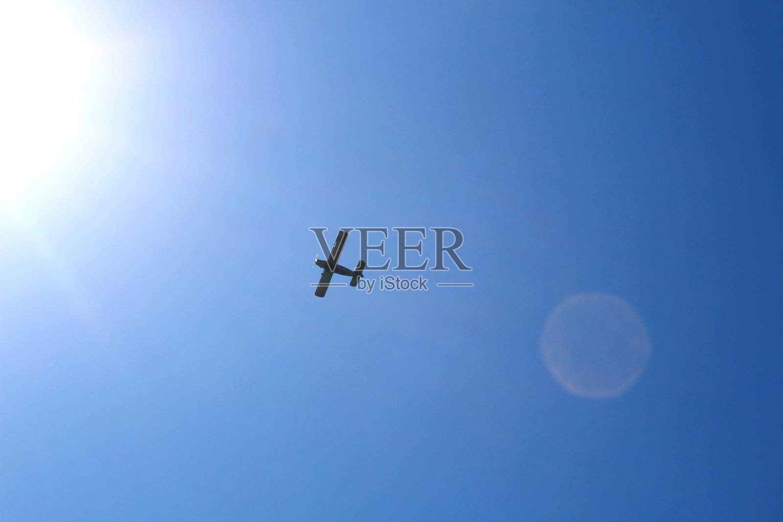 一架小飞机在蓝天上飞行。照片摄影图片