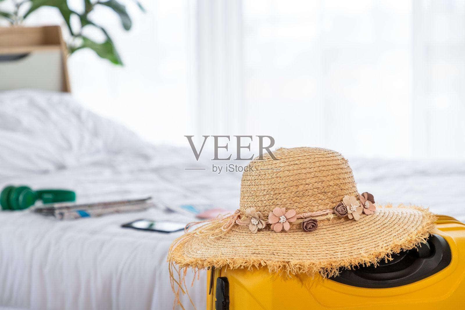 草帽上的黄色行李箱，模糊的卧室背景，为暑假旅行准备的概念照片摄影图片