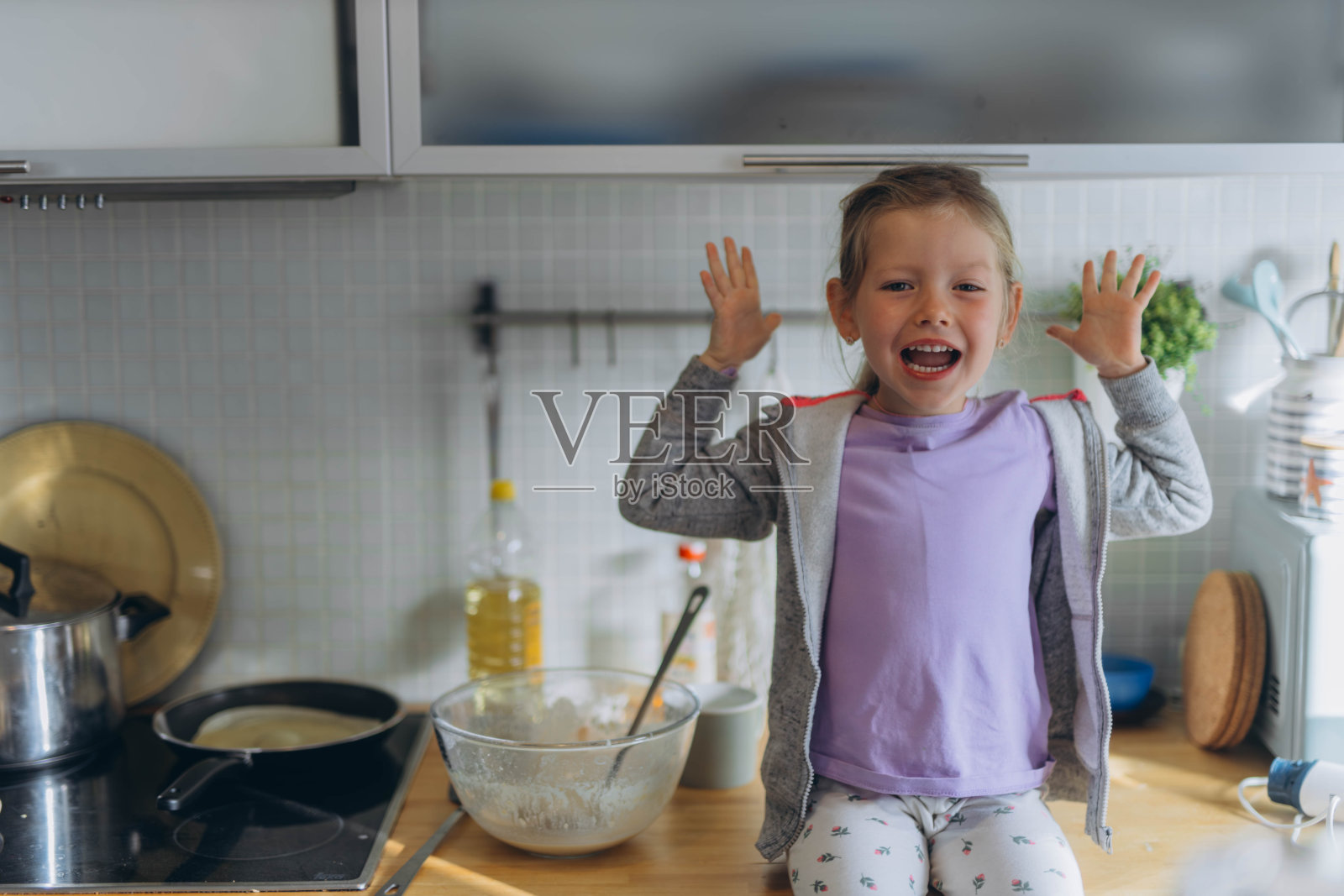 可爱的小女孩在家里的厨房里做煎饼。儿童烹饪概念照片摄影图片