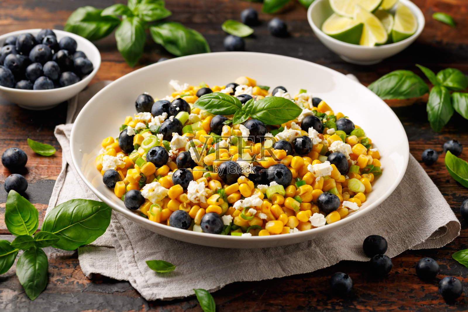 木桌上白色盘子里的蓝莓玉米羊乳酪沙拉。健康的食物照片摄影图片