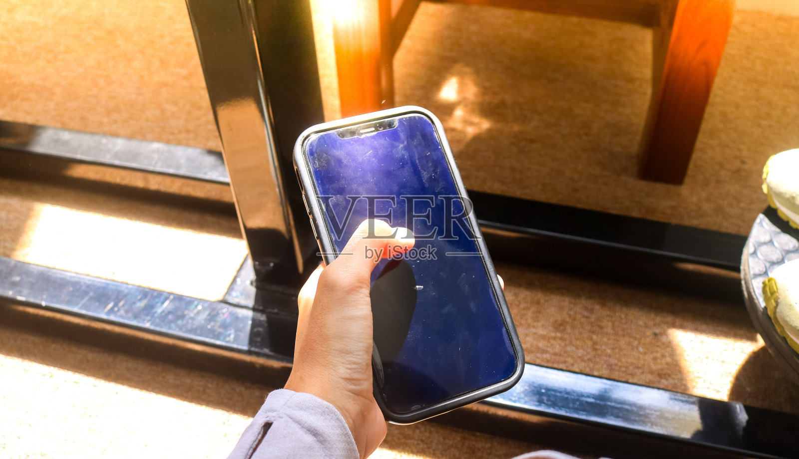 女人手持触摸手机屏幕的唯美阳光，女孩手持手机近景，科技与商业理念背景。照片摄影图片