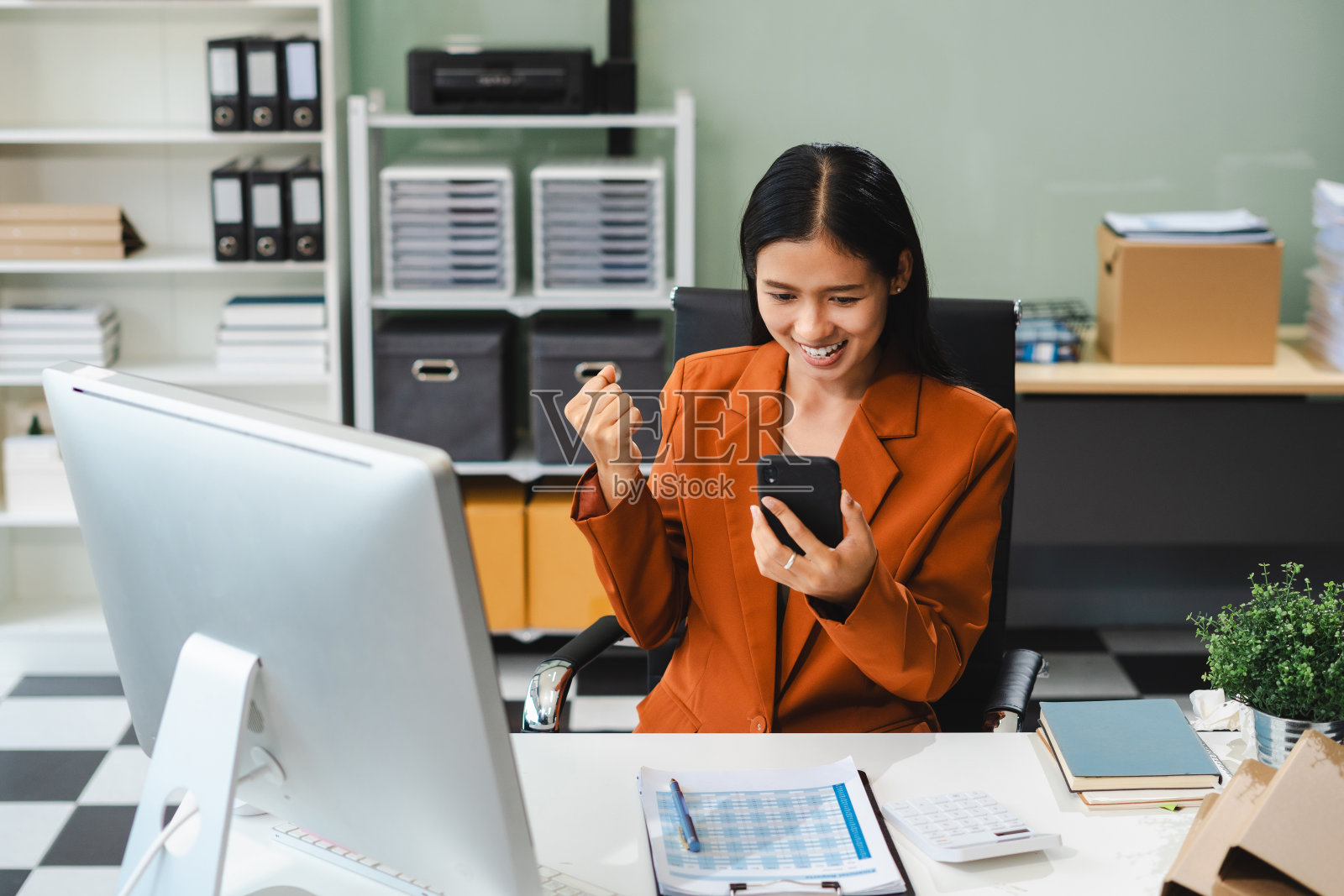 亚洲的商业女性从她们出色的财务业绩中获得灵感，在现代化的办公室里用电脑工作，她们对商业成功感到兴奋。照片摄影图片