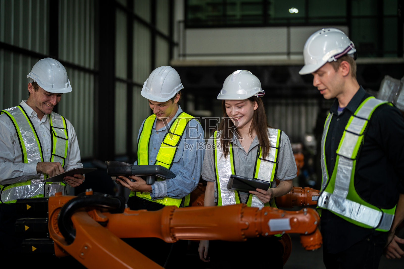 工厂工程师检查机器。自信团队成熟的商人用笔记本电脑站在工业机械臂旁，商人高空检测生产电子零件装置的技术。照片摄影图片