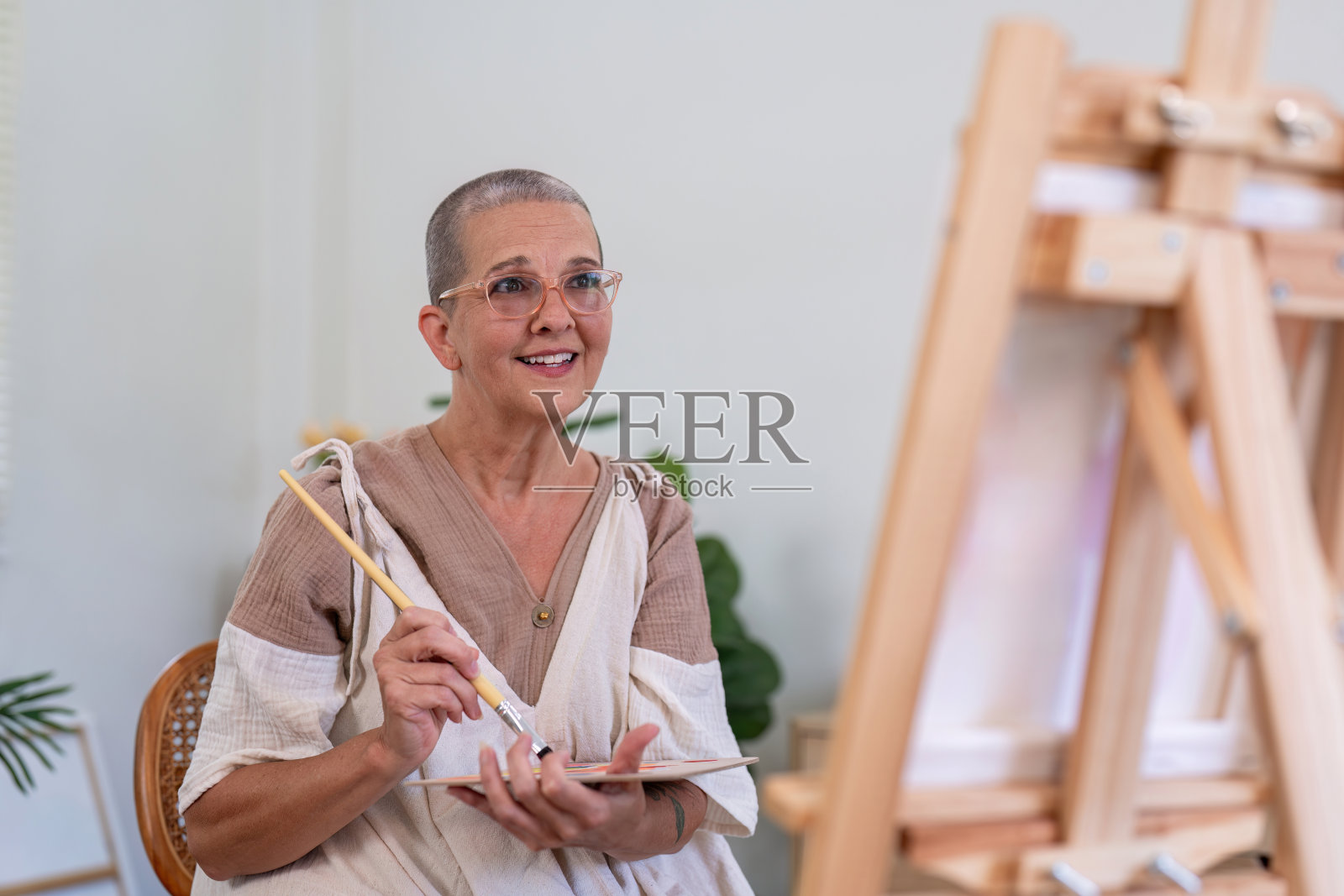 在家画布上画画的老年妇女，从事艺术创作活动，微笑快乐，老年生活方式和爱好照片摄影图片