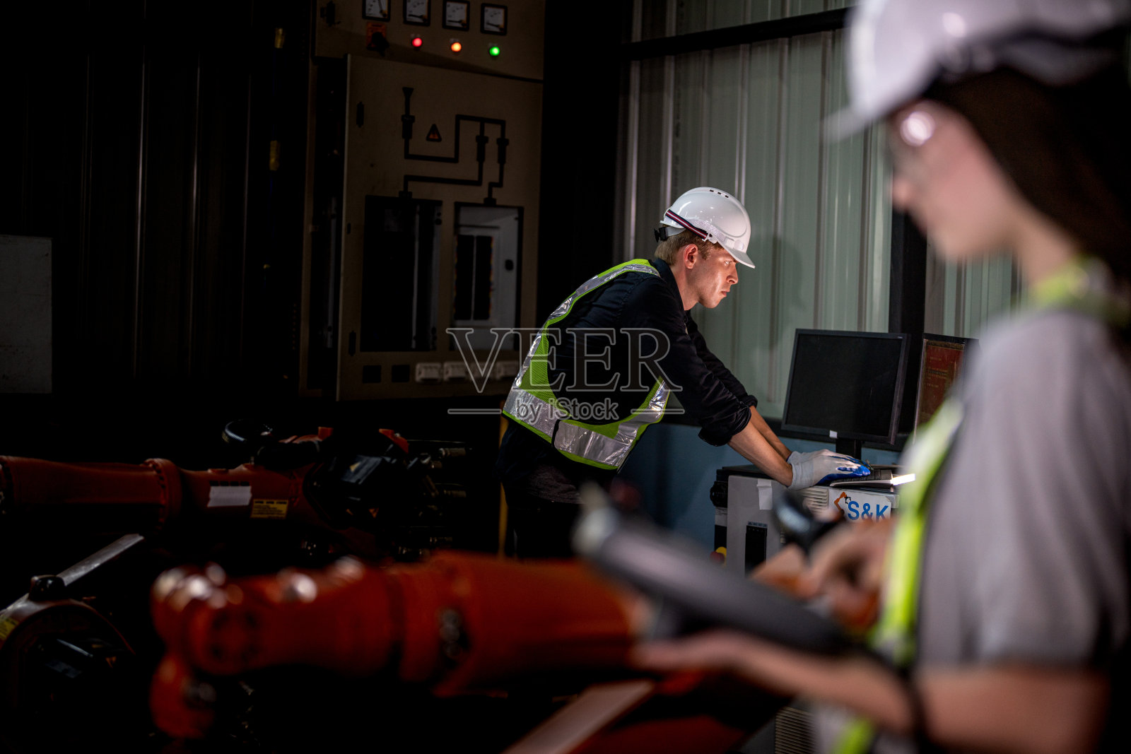 团队工程师用智能平板电脑检查机器。工人在重型机械机械臂上工作。工业工厂的远程系统焊机。人工智能概念。照片摄影图片