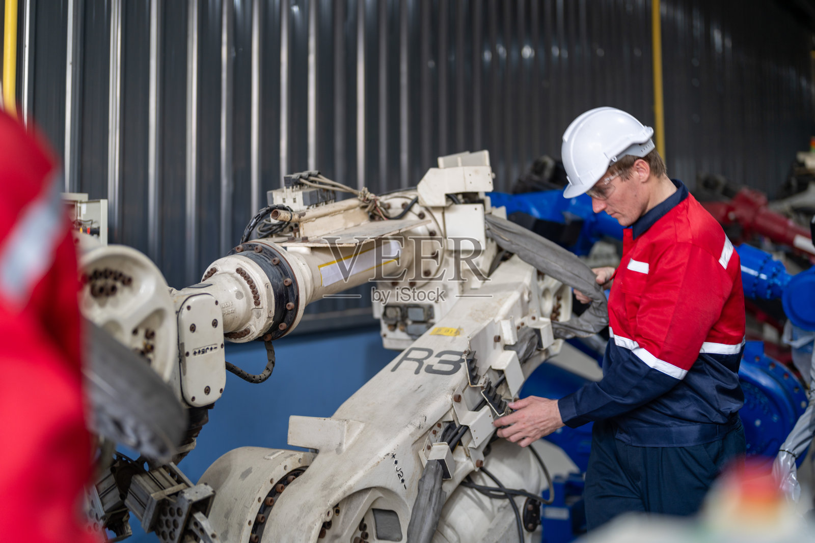 在一家工厂里，男工程师正在维护自动机械臂机。工人检查和修理自动机械手。技术员检查工厂机器的维修情况。照片摄影图片