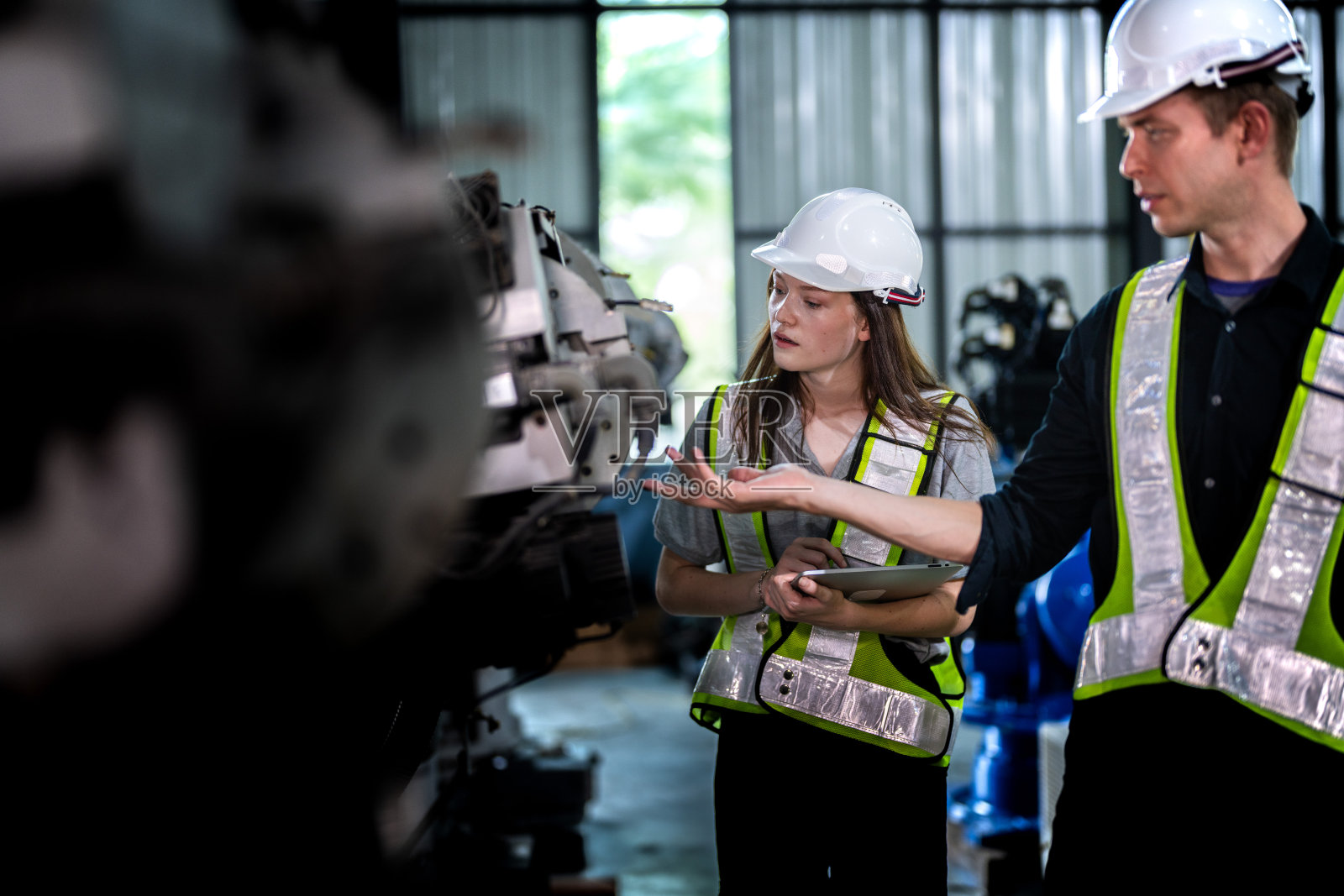 工厂工程师检查机器。自信团队成熟的商人用笔记本电脑站在工业机械臂旁，商人高空检测生产电子零件装置的技术。照片摄影图片