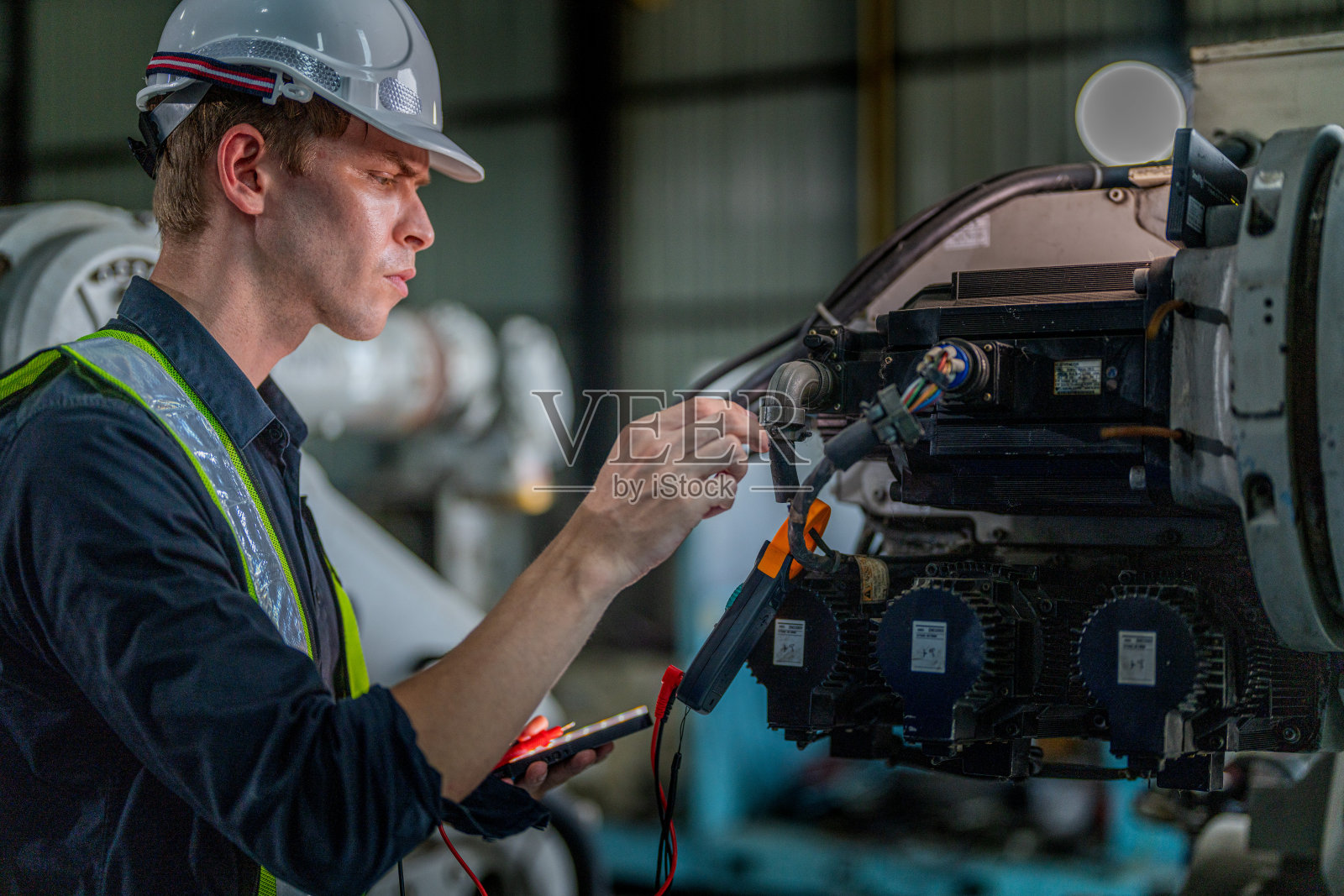 在一家工厂里，男工程师正在维护自动机械臂机。工人检查和修理自动机械手。技术员检查工厂机器的维修情况。照片摄影图片