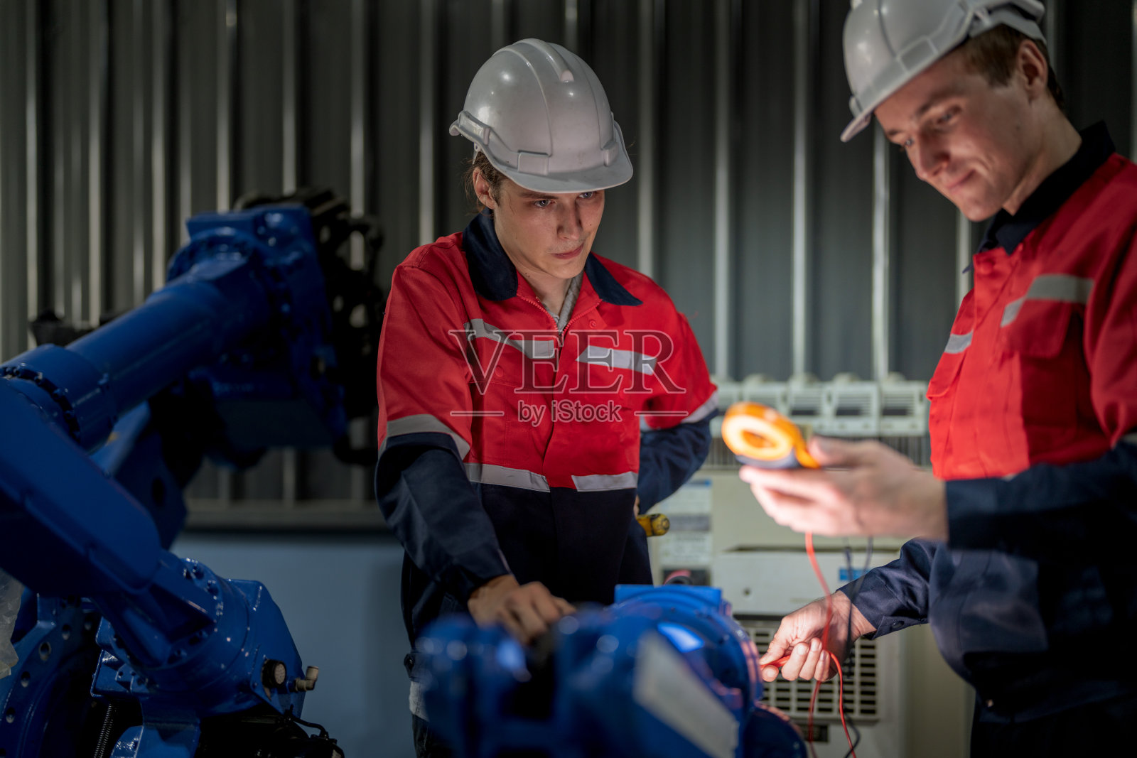 在一家工厂里，男工程师正在维护自动机械臂机。工人检查和修理自动机械手。技术员检查工厂机器的维修情况。照片摄影图片