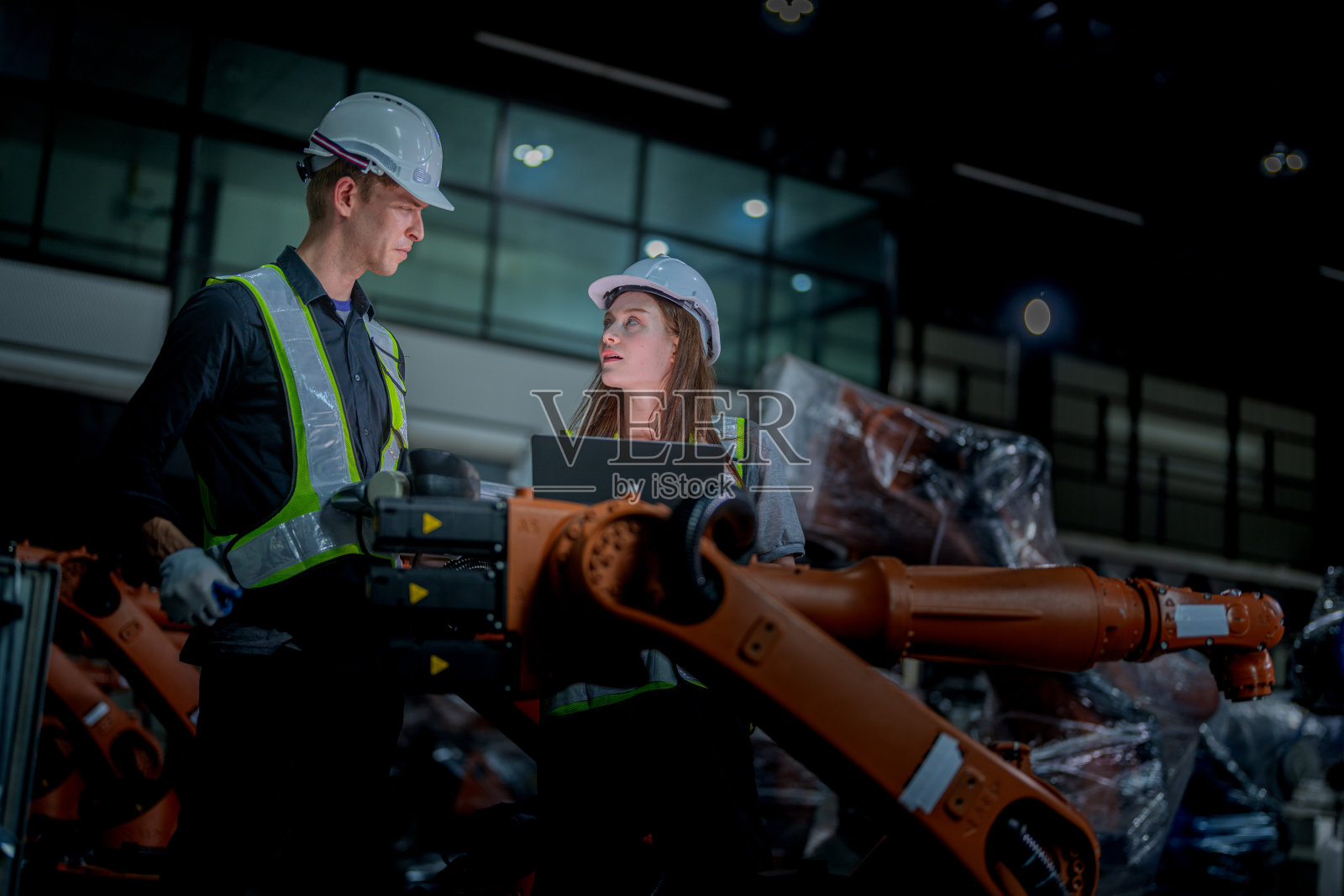 团队工程师用智能平板电脑检查机器。工人在重型机械机械臂上工作。工业工厂的远程系统焊机。人工智能概念。照片摄影图片