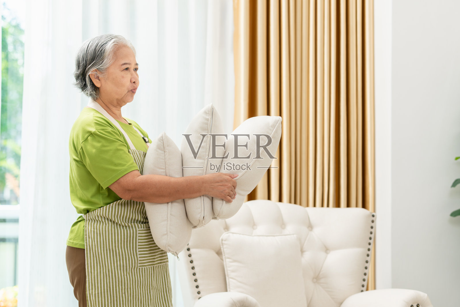 女管家打扫房间，亚洲资深女管家，专业女管家整理沙发枕头照片摄影图片