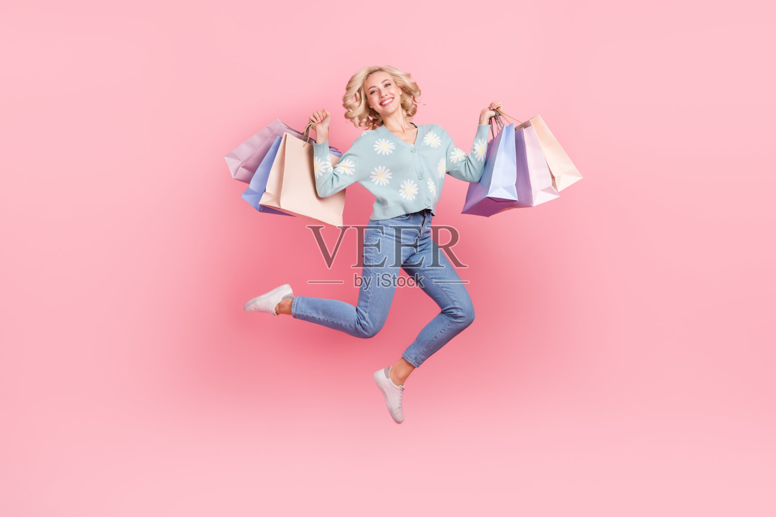 可爱的兴奋的女士穿着花印花开衫跳高上升的讨价还价孤立的粉红色背景的全长照片照片摄影图片