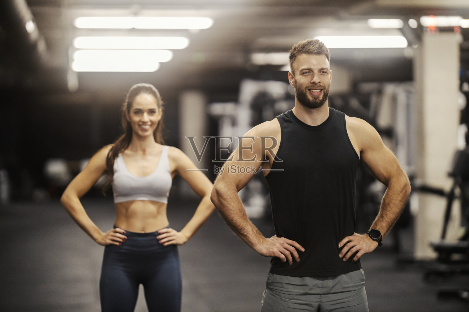 健美肌肉运动员站在健身房里，双手叉腰。照片摄影图片