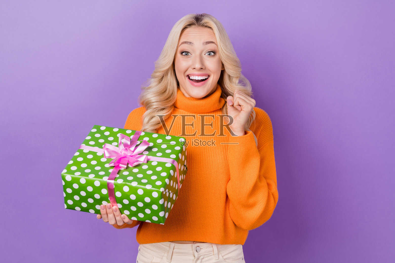 时髦的喜悦的人的肖像举起拳头握住收到理想的礼盒孤立在紫色的背景照片摄影图片