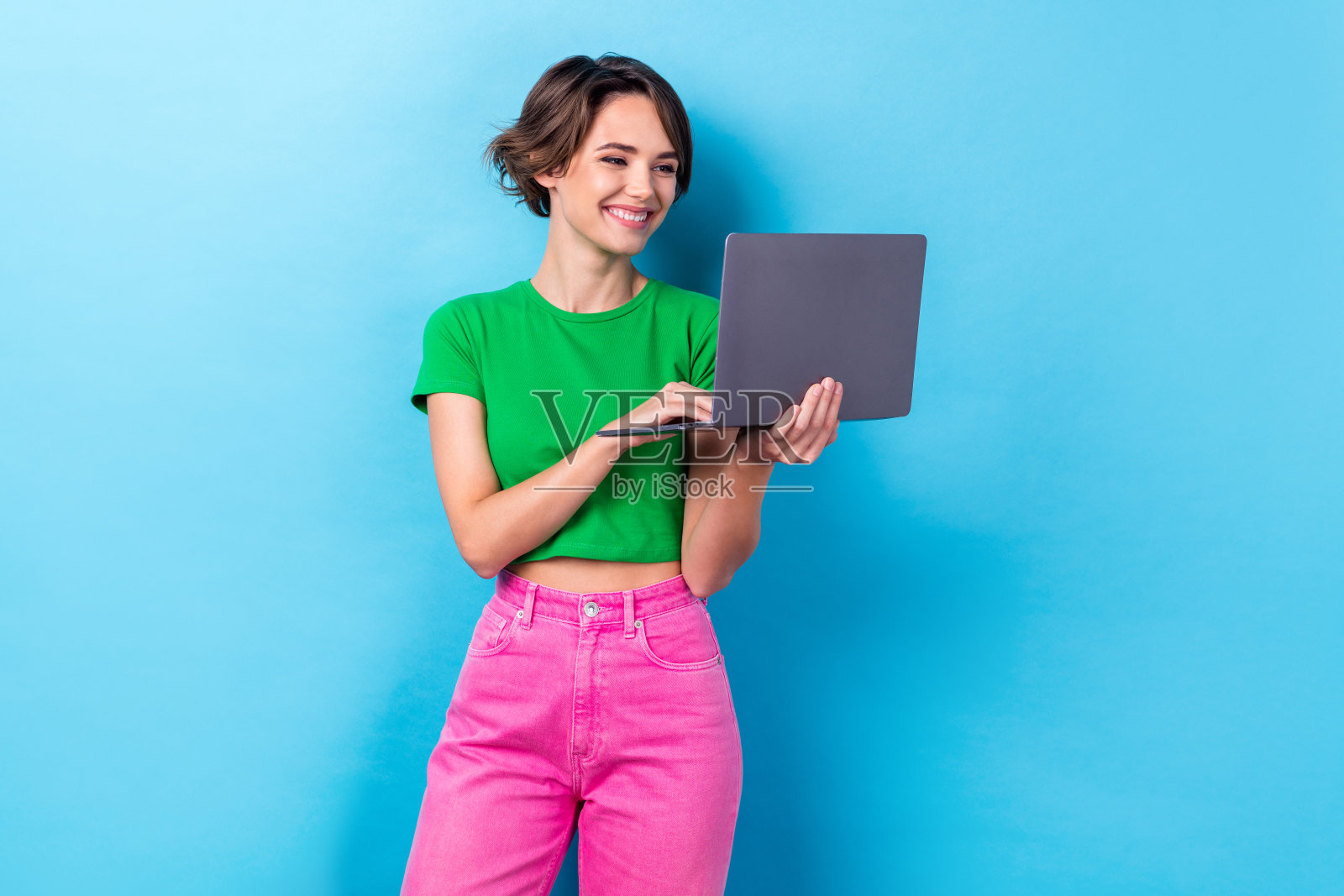 漂亮可爱的女人穿绿色t恤打字电子邮件现代设备孤立的蓝色背景的照片照片摄影图片