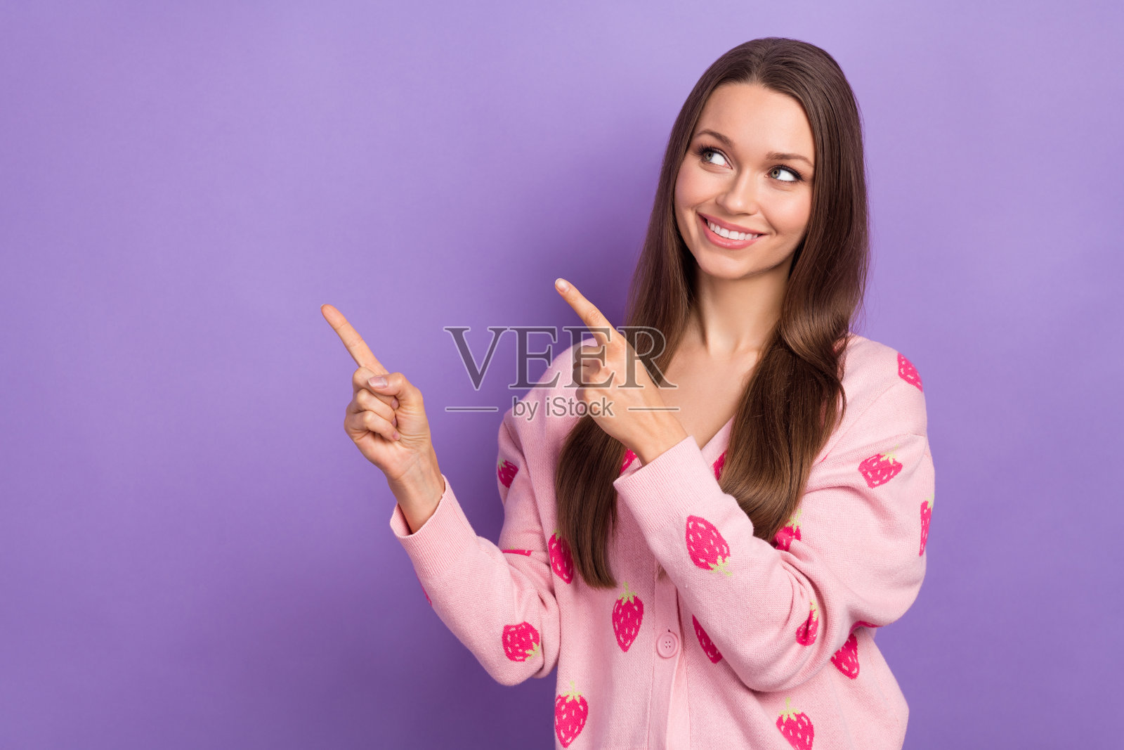 照片中可爱的梦幻女孩穿着浆果印花开衫看着两个手指看着空白的空间孤立的紫罗兰色背景照片摄影图片