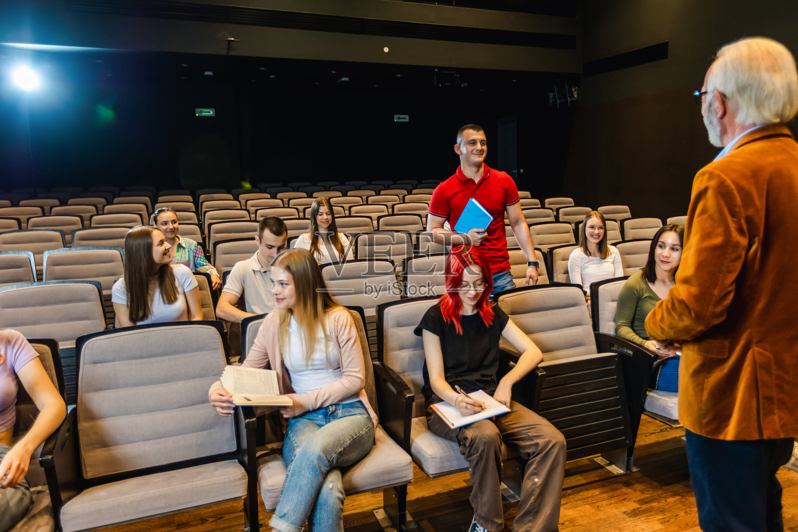 男学生站起来回答老教授的问题。照片摄影图片