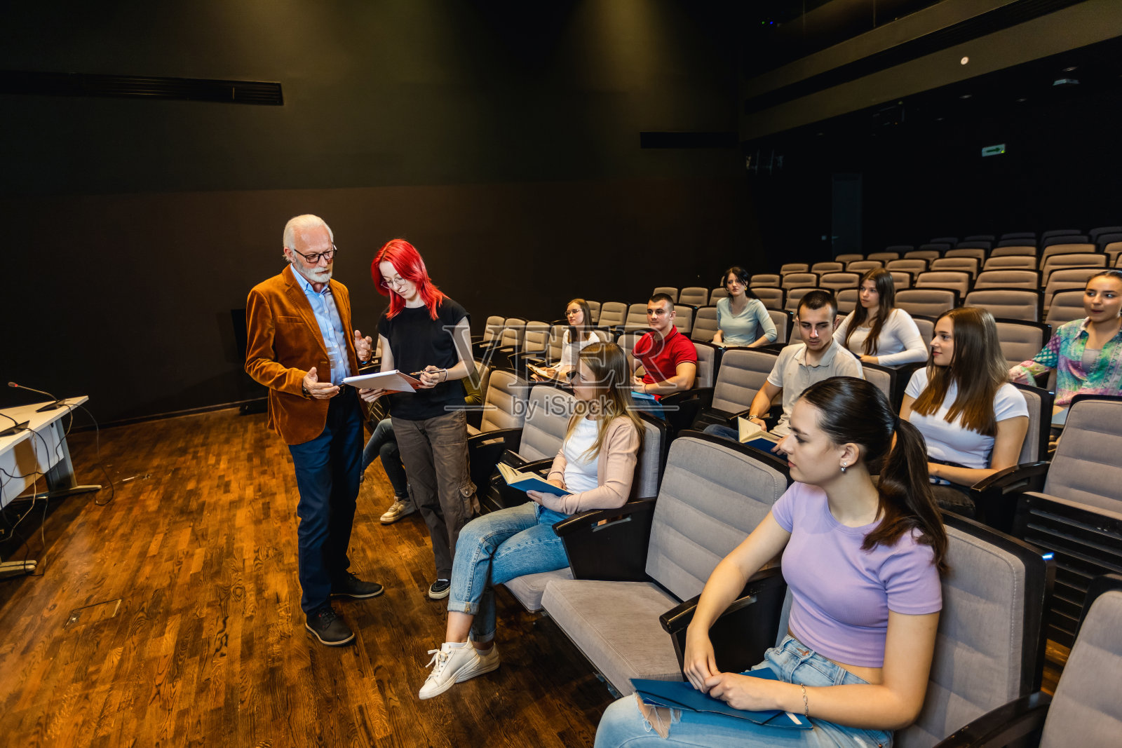 红发女学生在问关于讲座的问题。上了年纪的男教授给学生答题讲课。照片摄影图片